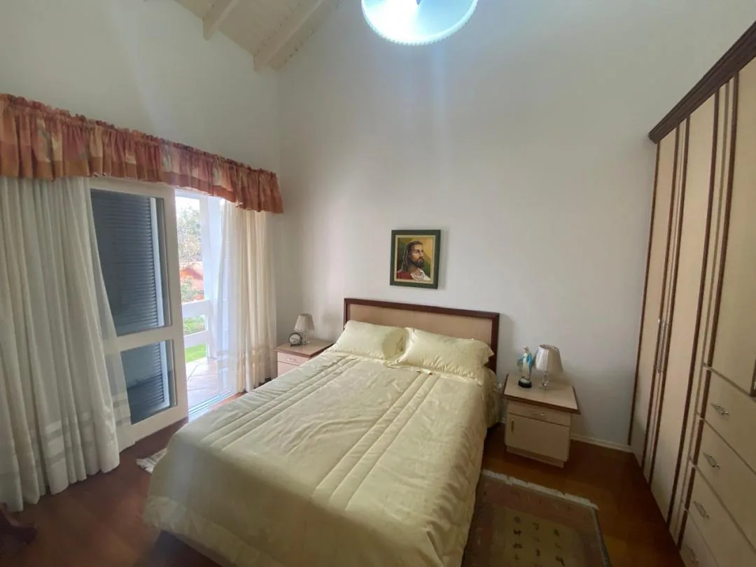 Quarto com cama de casal, roupeiro alto e porta envidraçada para a sacada