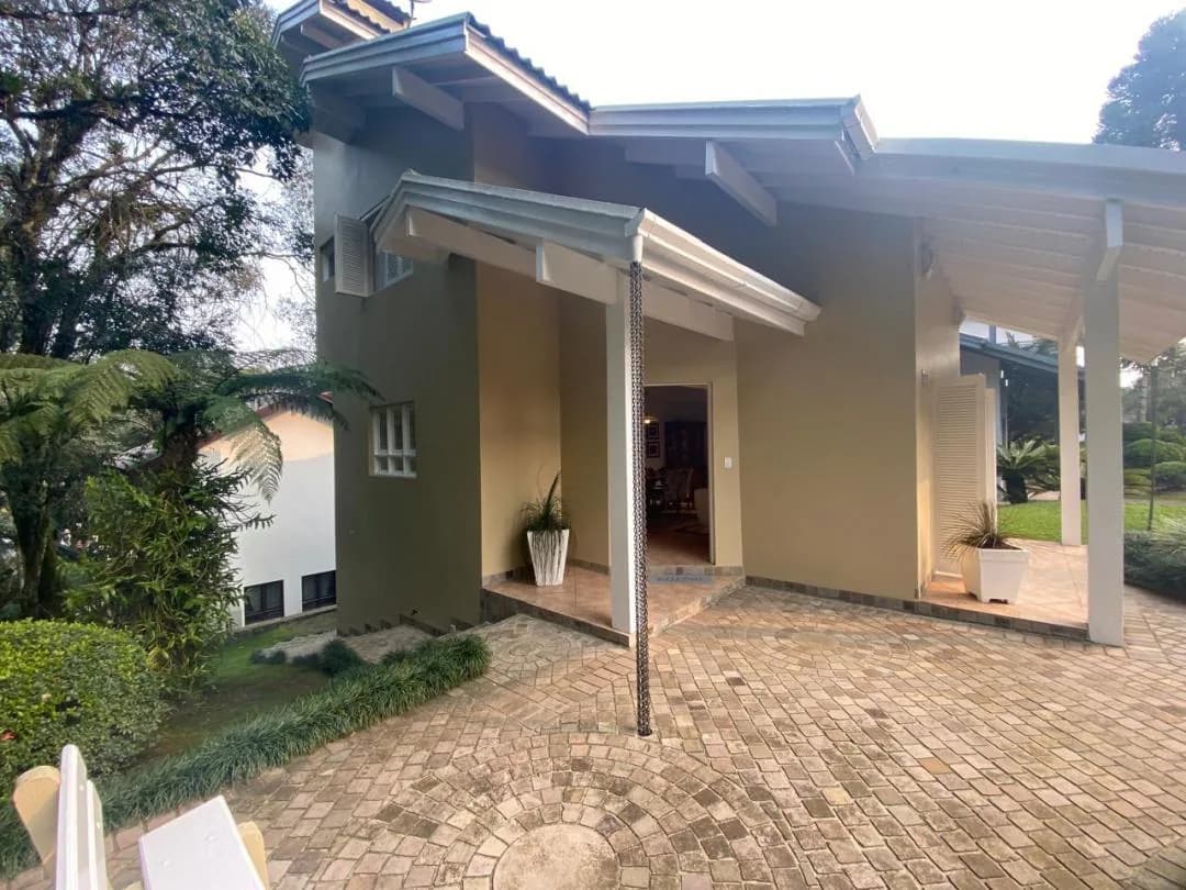 Lateral da casa com varanda coberta, vasos de plantas e pátio de pedra