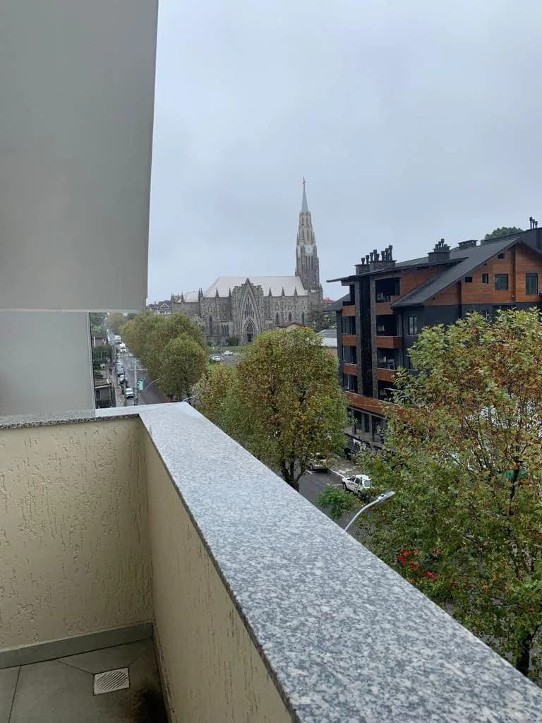 Sacada com parapeito de granito e vista para a Catedral de Pedra e a rua arborizada