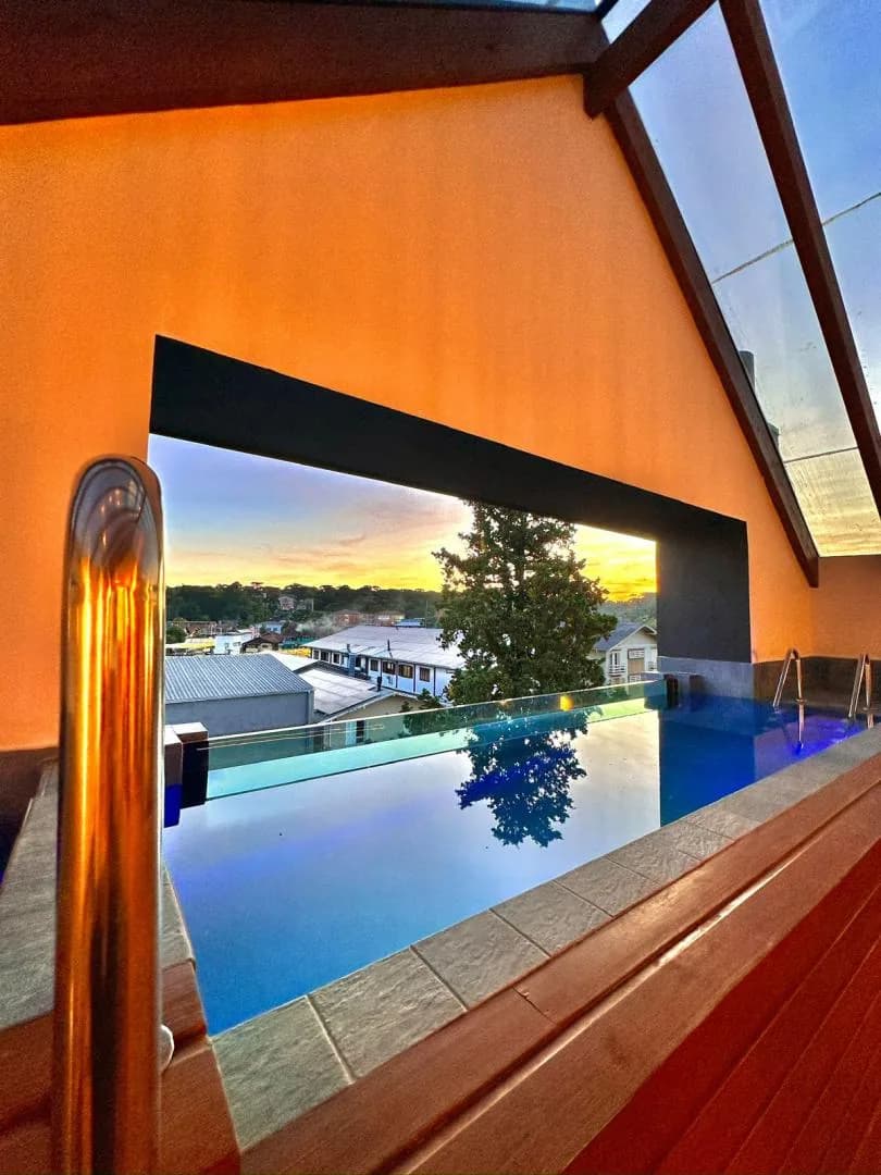 Piscina do terraço com borda de vidro e vista para a cidade ao pôr do sol