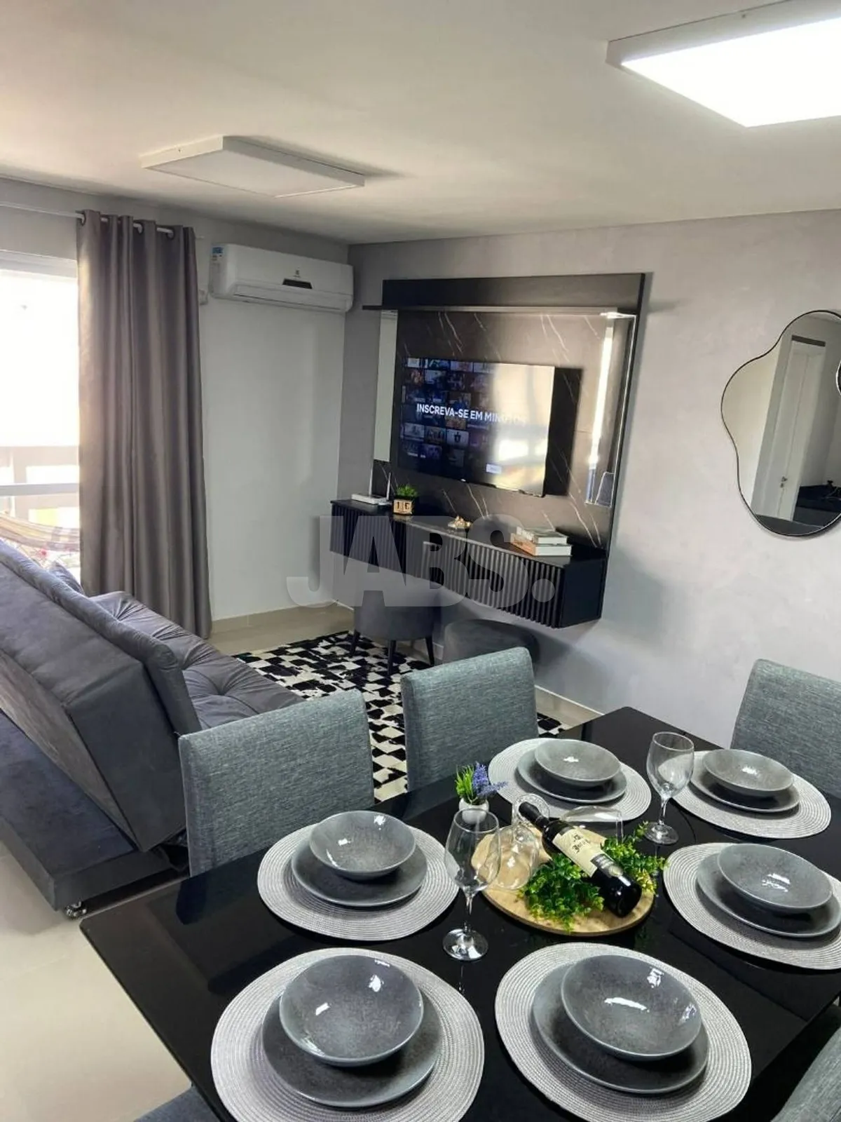 Mesa de jantar posta e sala com TV
