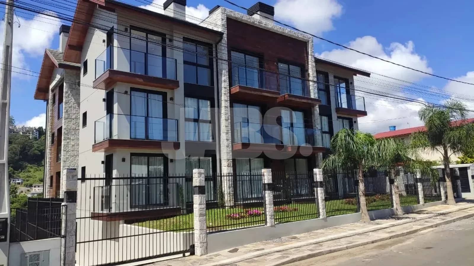 Fachada do prédio novo com pedra e sacadas de vidro