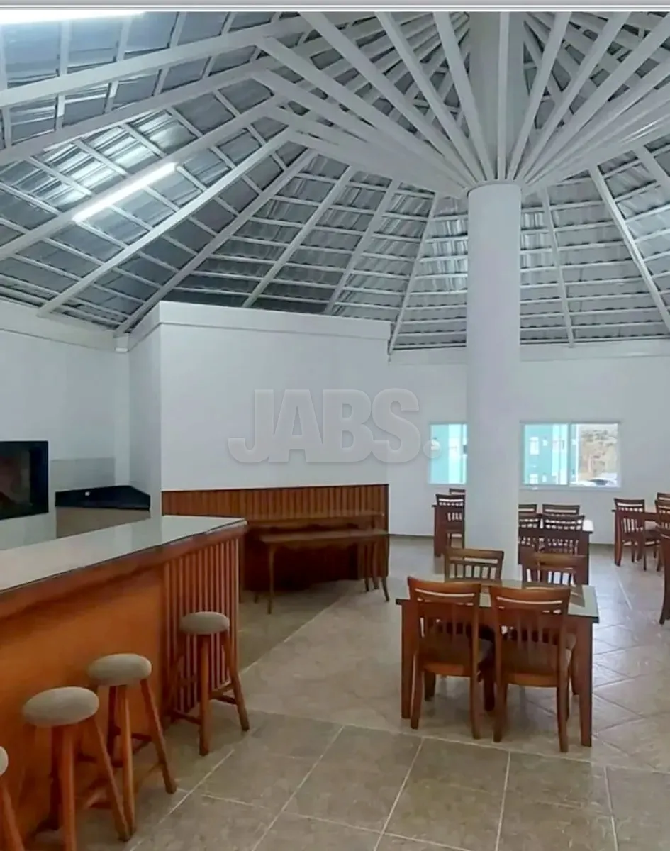 Salão de festas do condomínio com cozinha e mesas