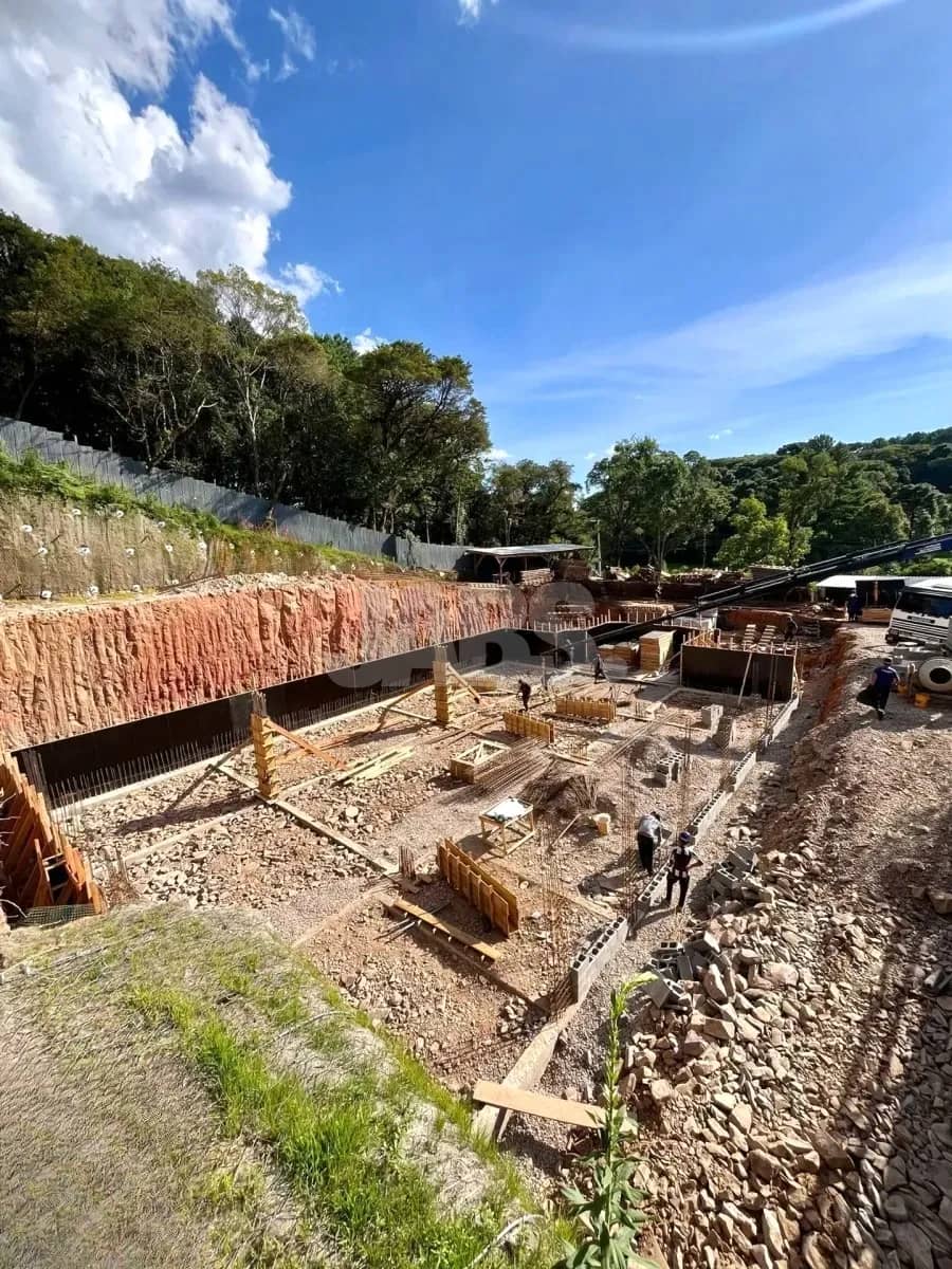 Obra no terreno, com as fundações em andamento e mata ao fundo