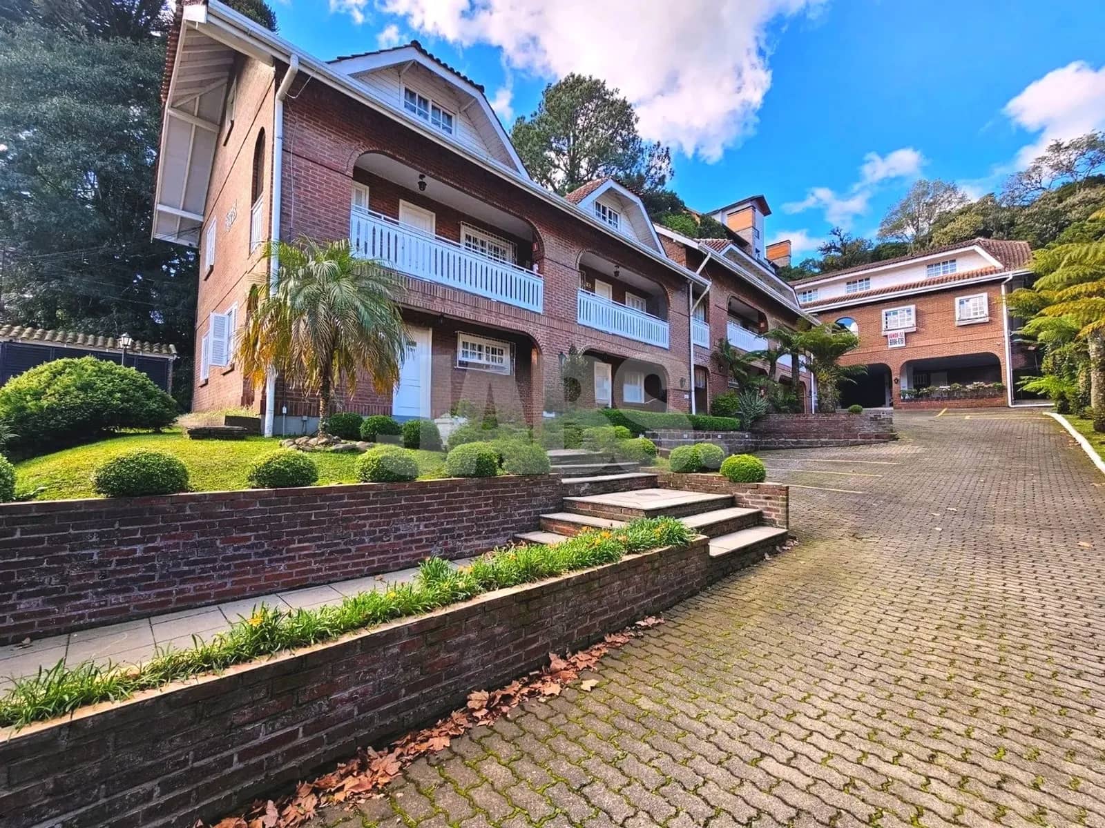 Condomínio com jardim e escadaria entre os blocos de tijolo