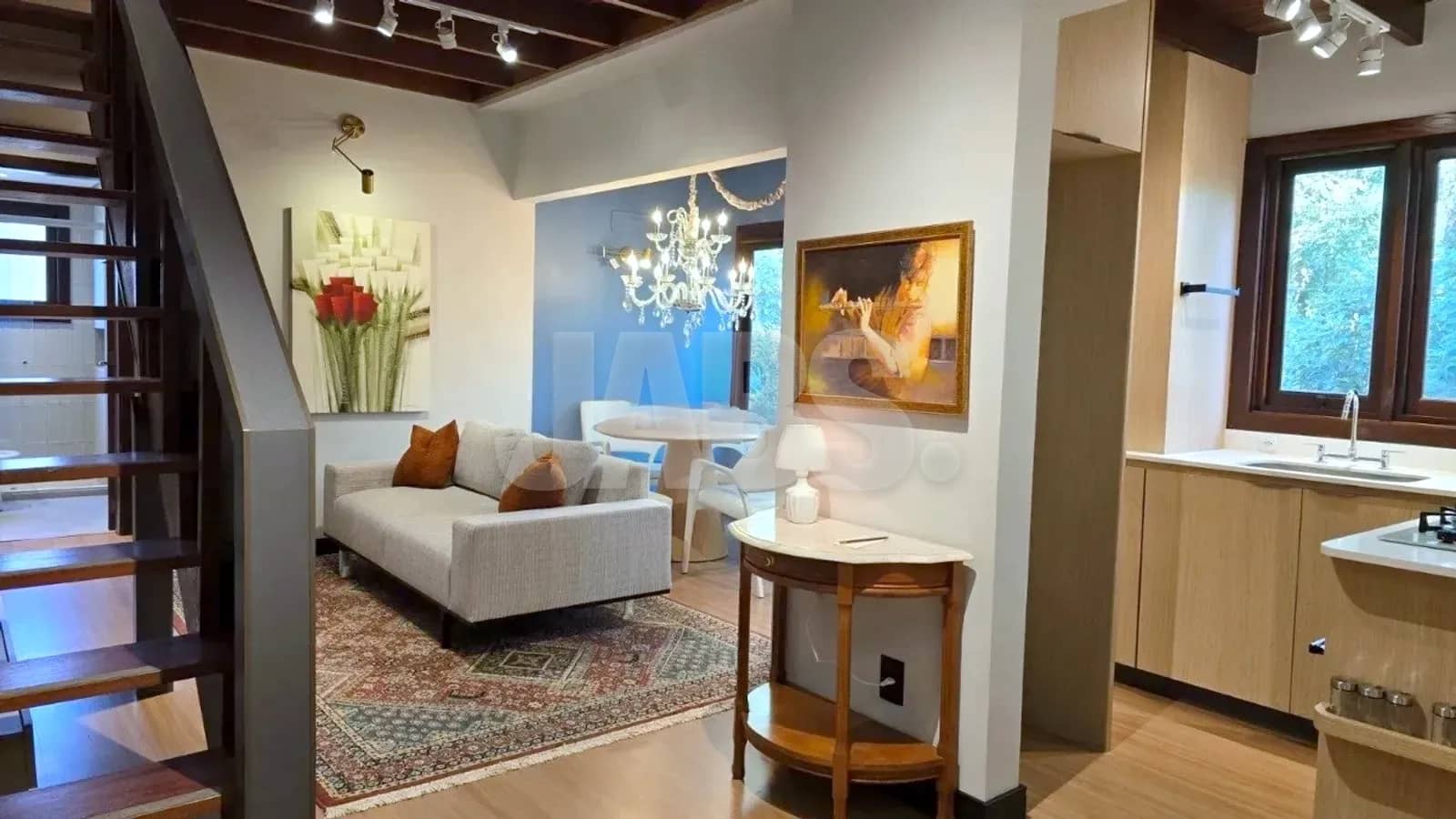 Sala integrada à cozinha, com forro de madeira e quadros nas paredes