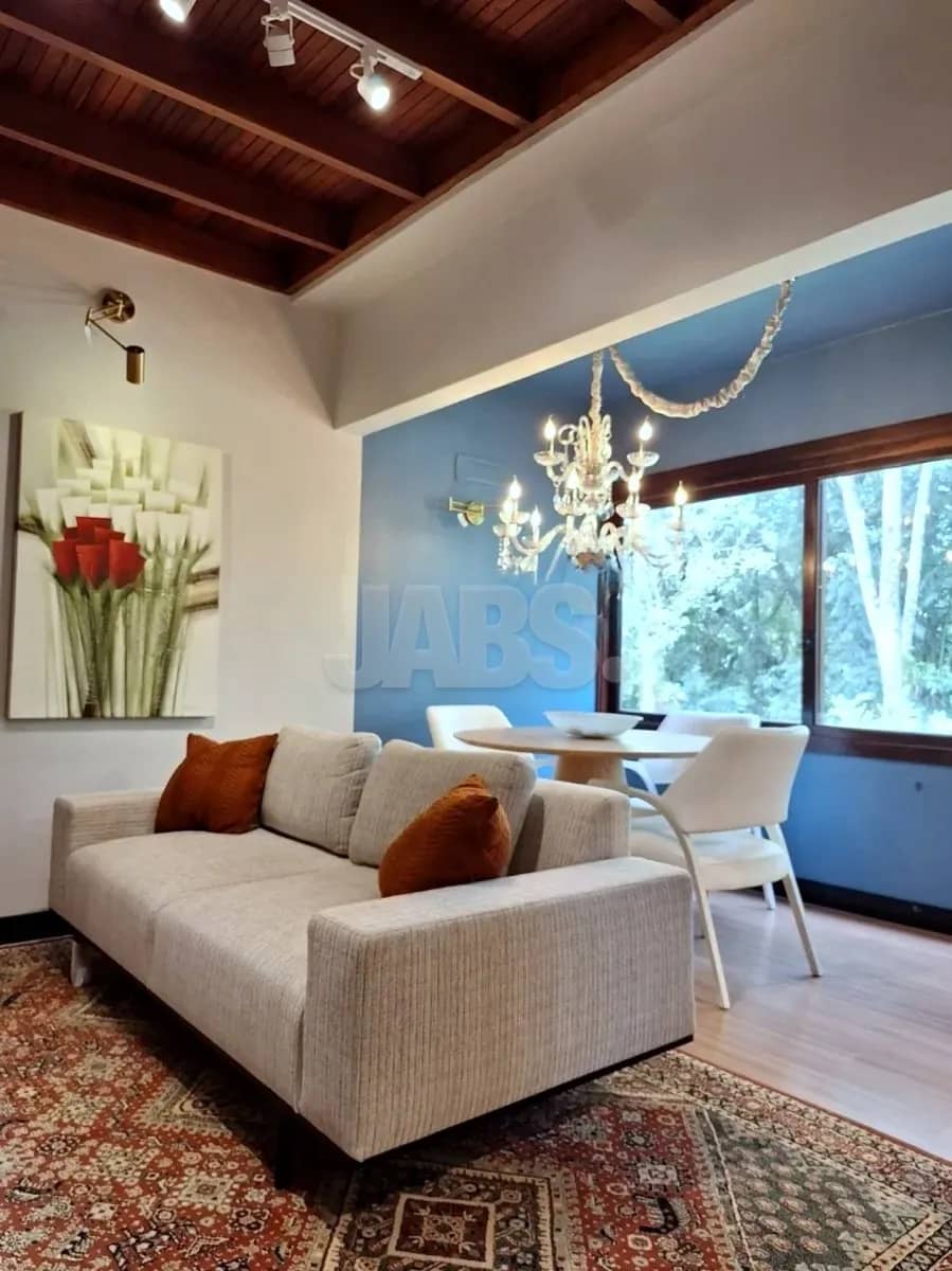 Sala com lustre de cristal, parede azul e mesa redonda junto à janela