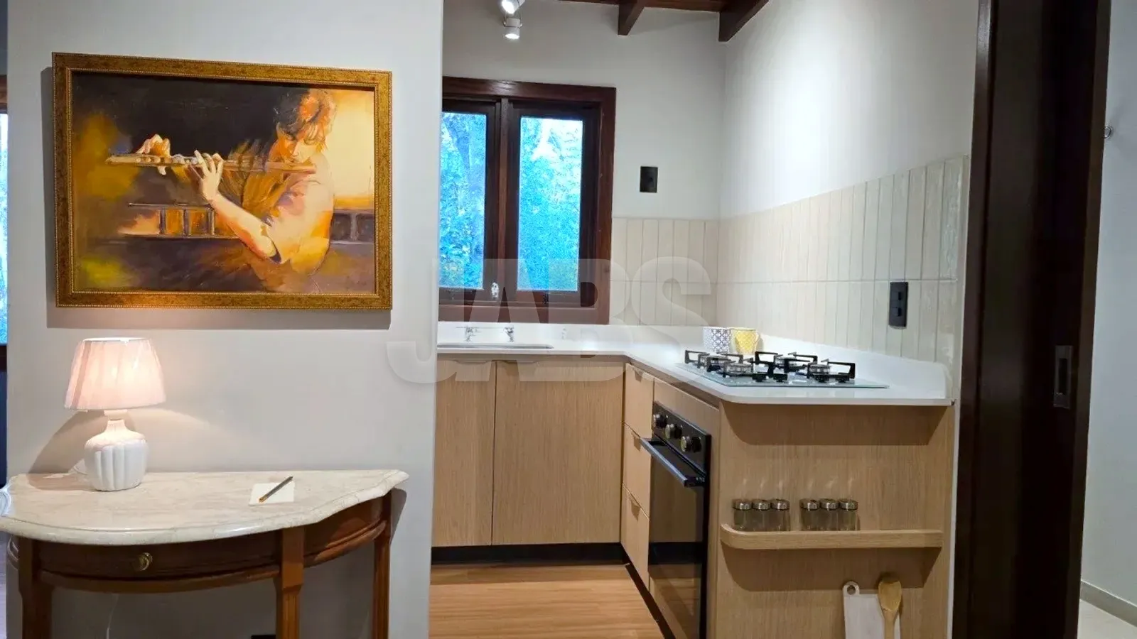 Cozinha com cooktop, forno embutido e armários em madeira clara