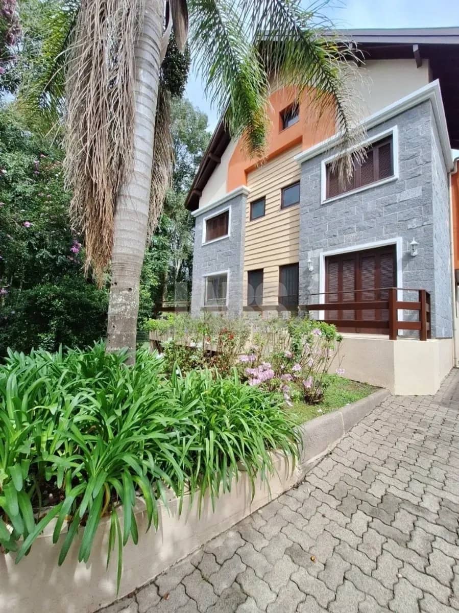 Fachada do prédio com pedra cinza, sacadas de madeira e palmeiras