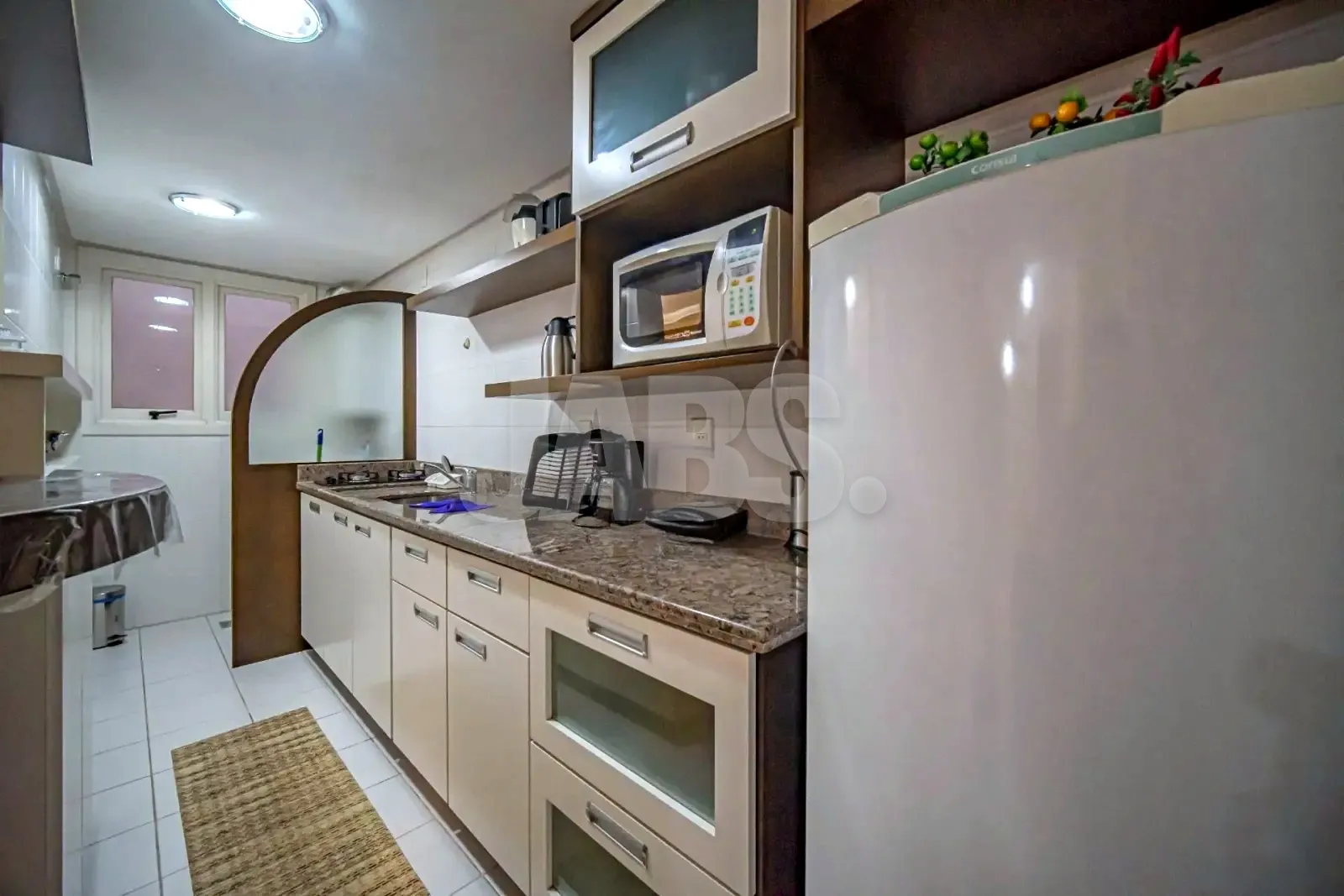 Cozinha com armários brancos, bancada de granito e prateleiras de madeira