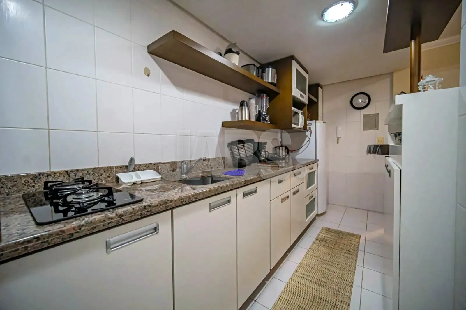 Cozinha com cooktop, pia de granito e armários claros