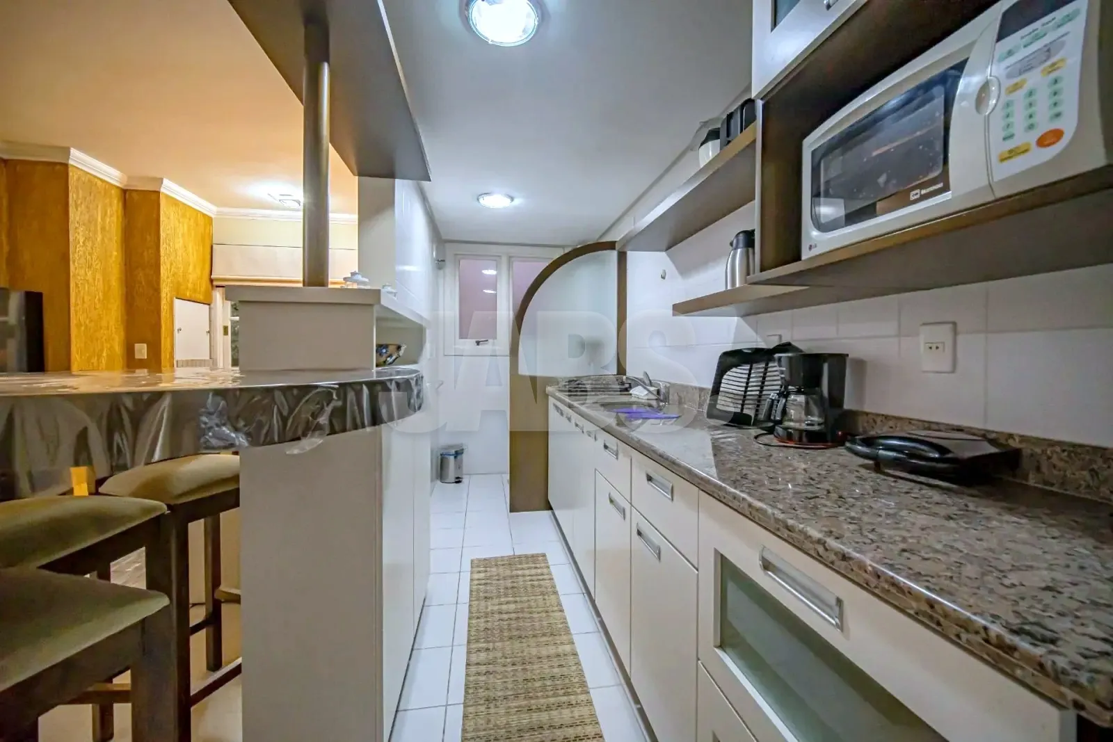 Cozinha vista do balcão, com micro-ondas e cafeteira