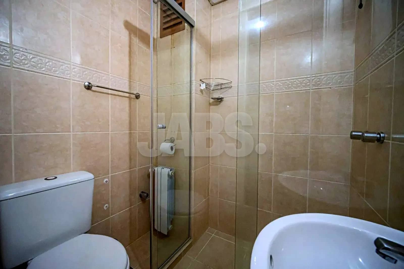 Banheiro com revestimento bege e box de vidro