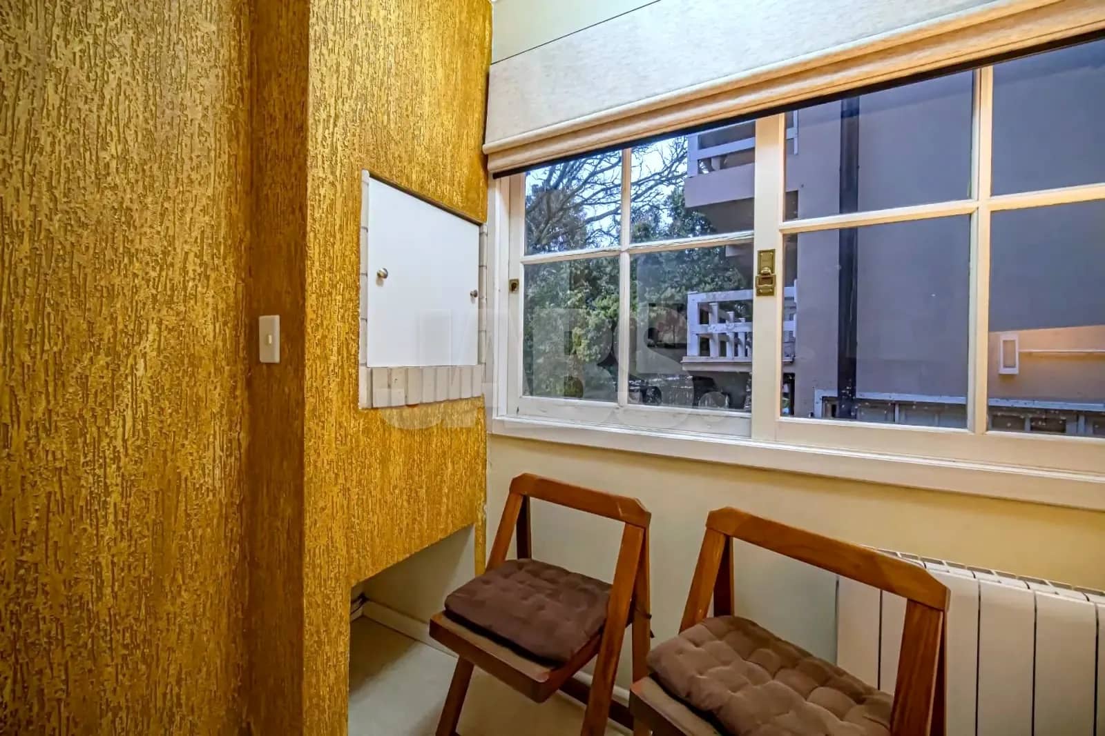 Recanto da sala com cadeiras de madeira junto à janela