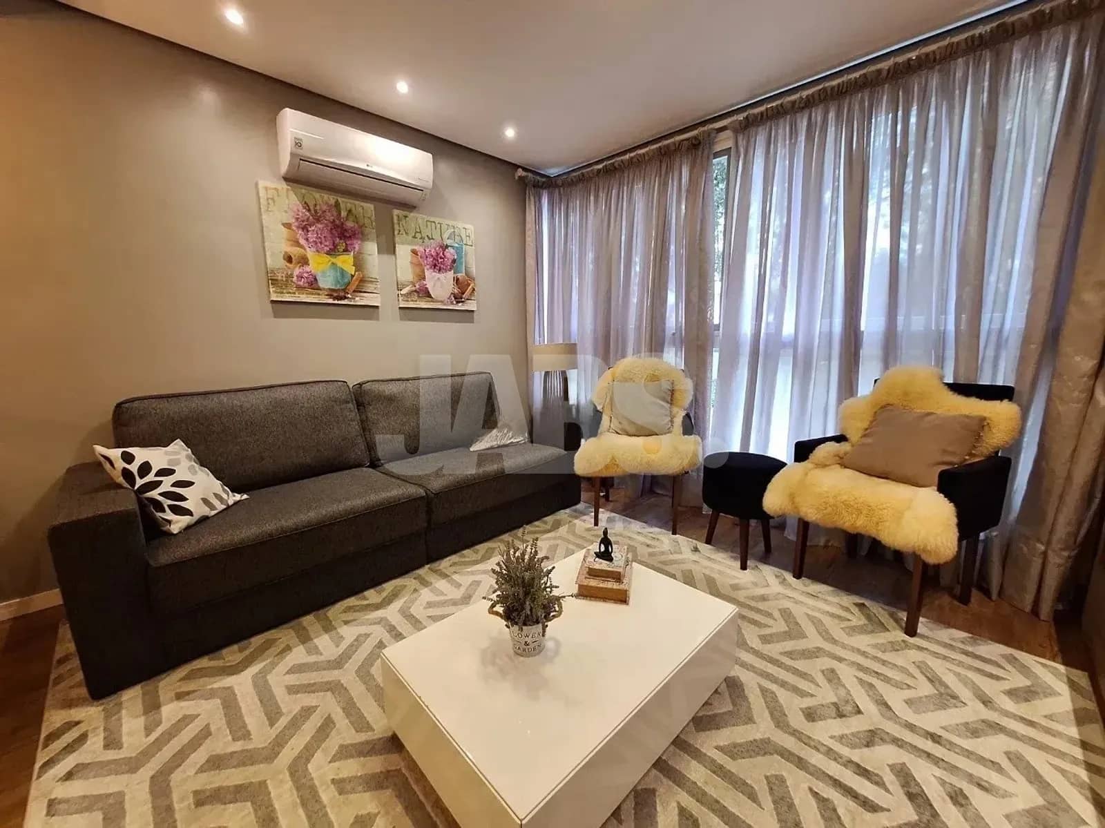 Sala com sofá, poltronas e janelas amplas