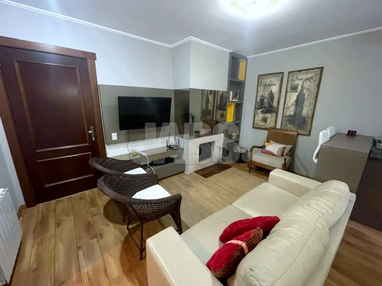 Sala de estar com TV, lareira revestida em branco e porta de madeira escura