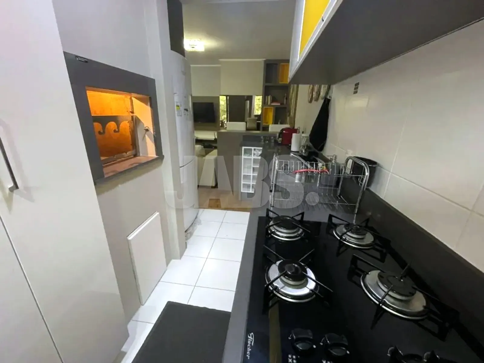 Cozinha com cooktop a gás, churrasqueira embutida e janela ao fundo