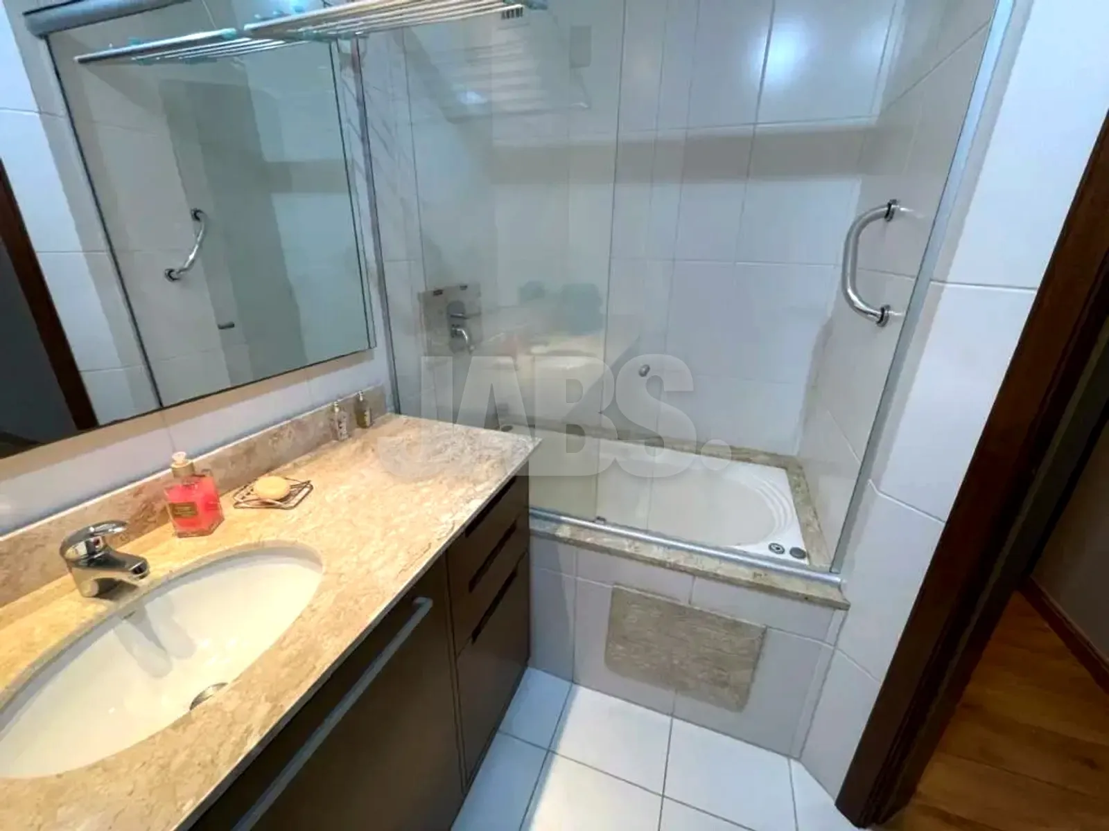 Banheiro da suíte com bancada de granito, espelho amplo e box de vidro