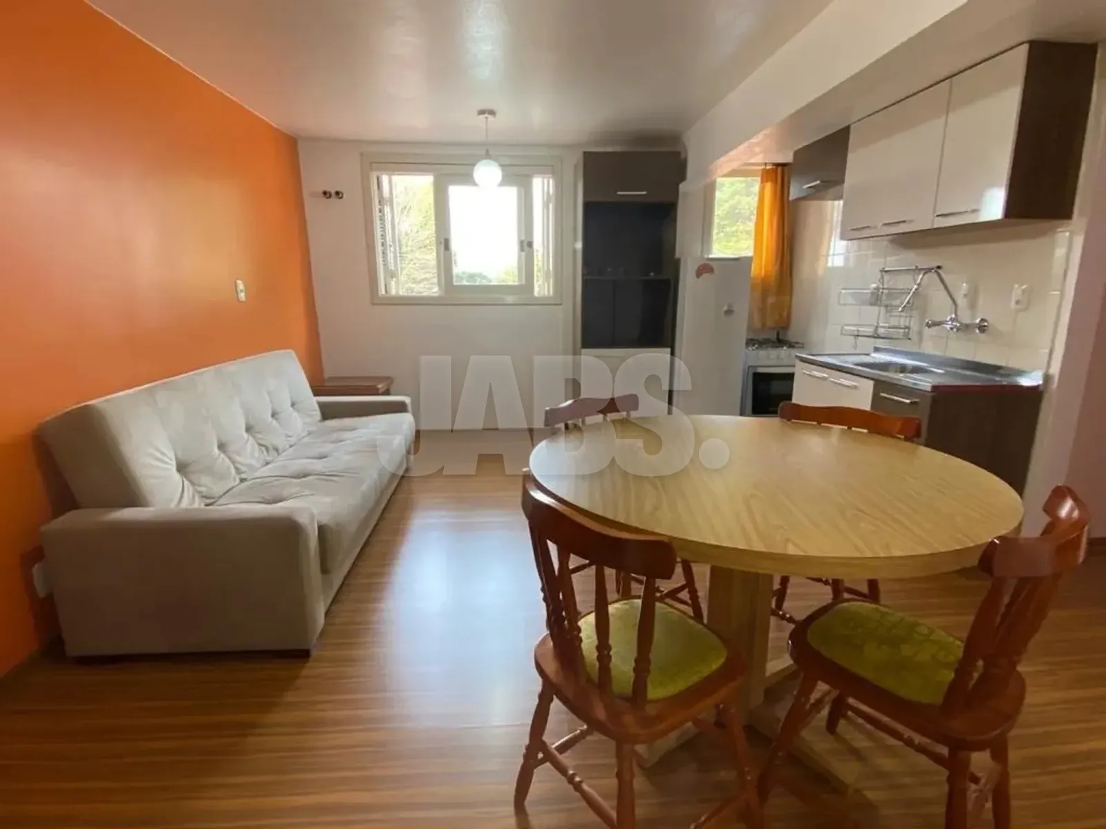 Sala e cozinha integradas com sofá e mesa de jantar redonda