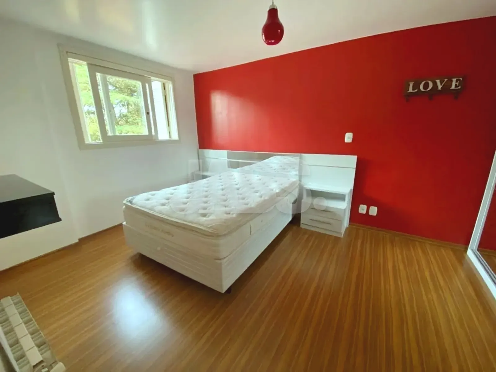 Segundo cômodo com cama de solteiro e parede vermelha