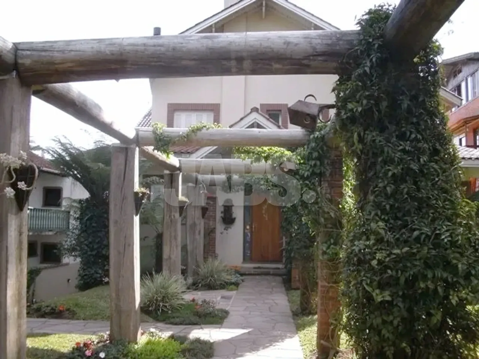 Entrada com pergolado de madeira e trepadeiras
