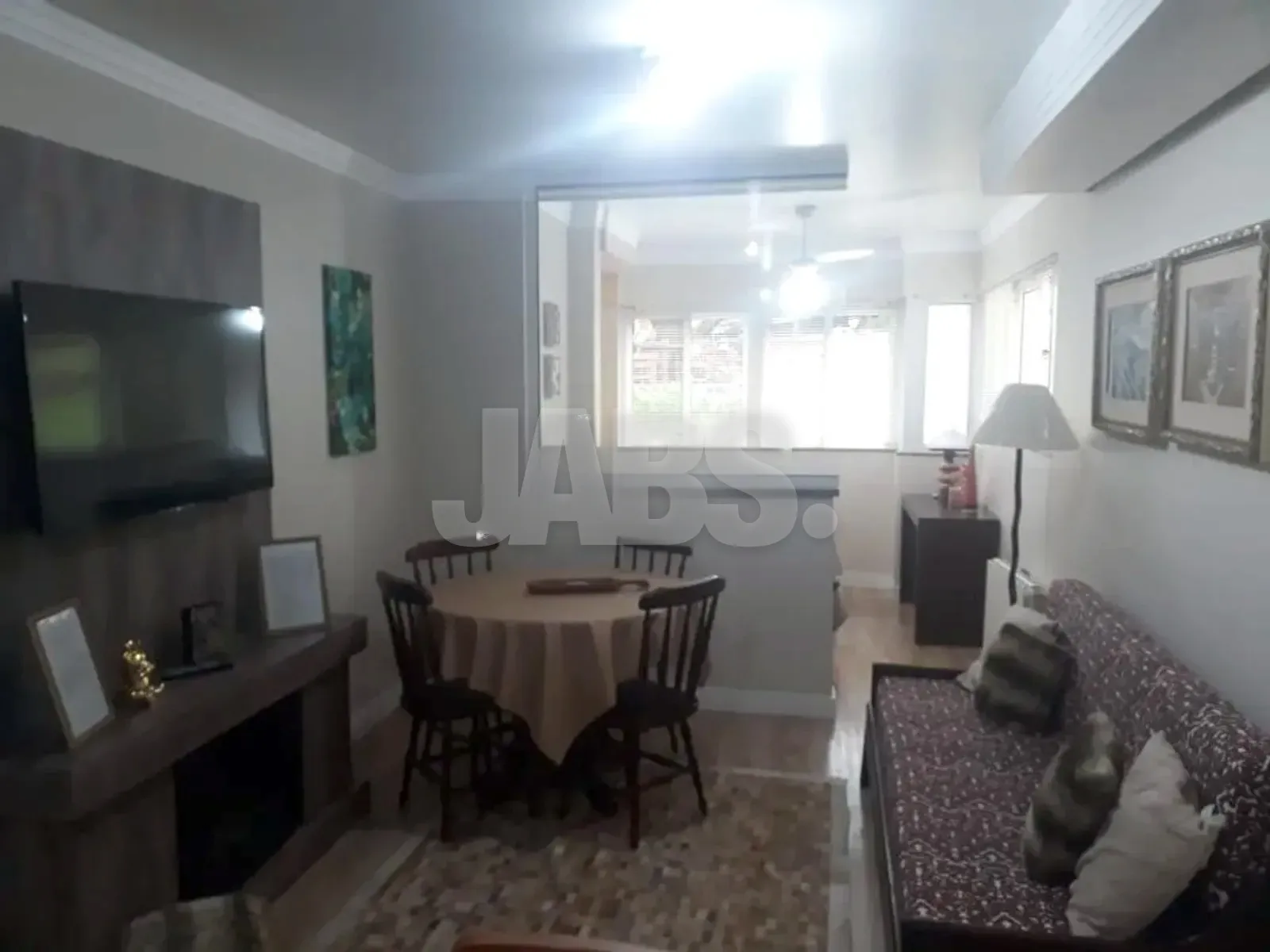 Sala com lareira, TV, mesa redonda de jantar e sofá estampado junto à janela