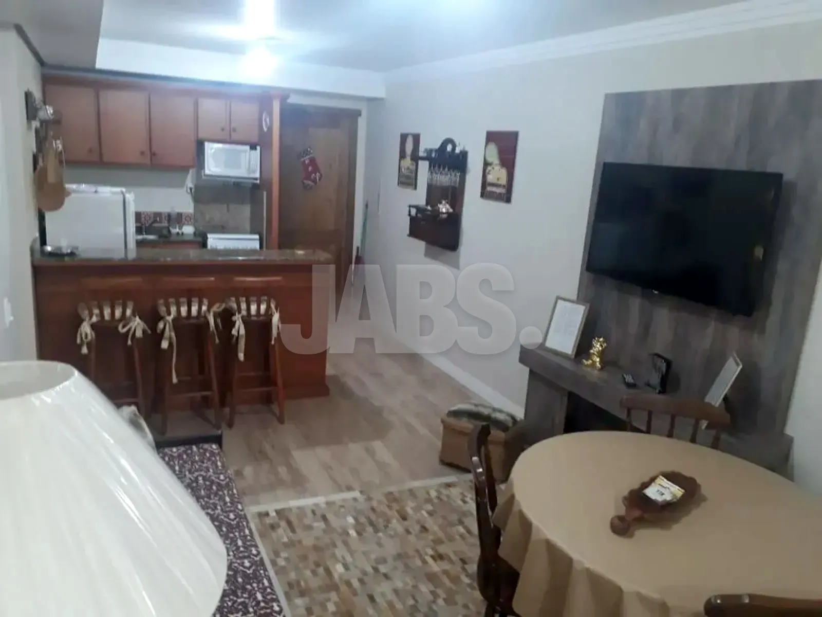 Sala integrada à cozinha americana, com balcão de madeira e banquetas