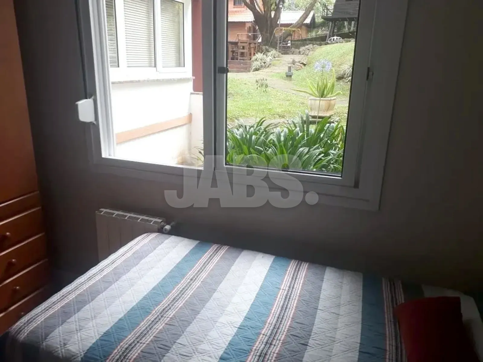 Dormitório com janela aberta para o jardim do condomínio