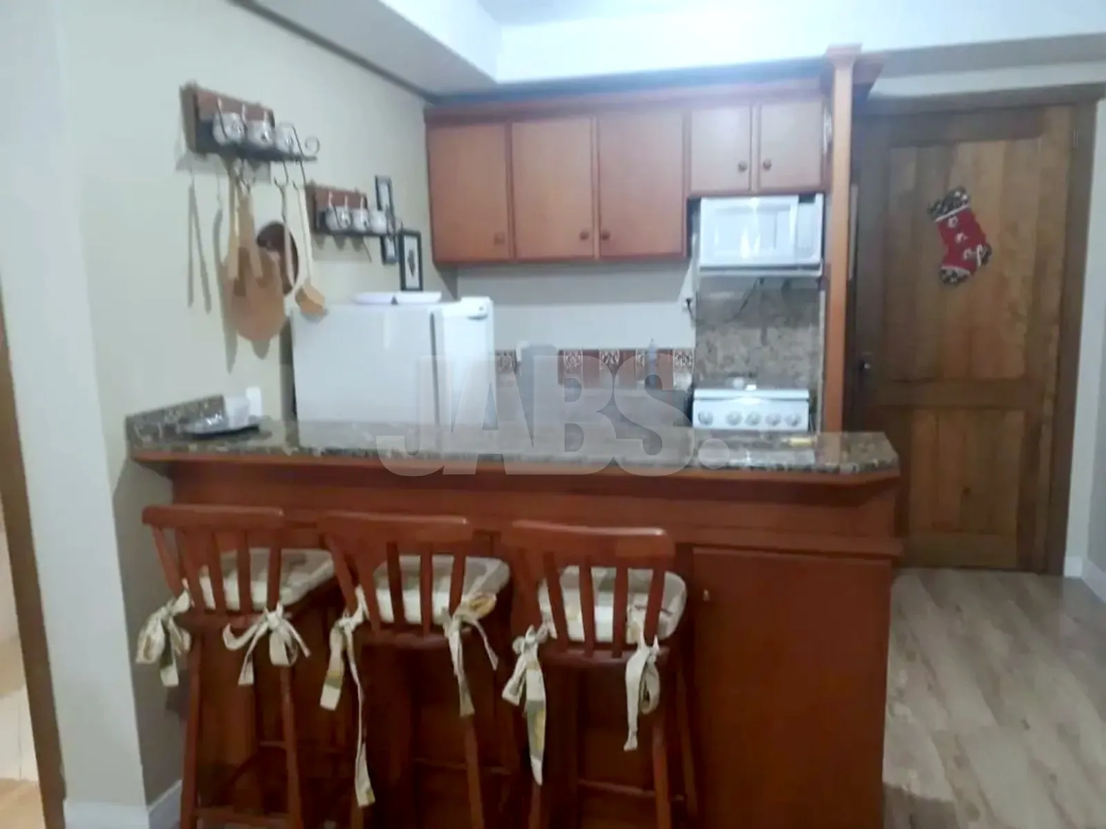 Cozinha americana com armários de madeira, micro-ondas e balcão com banquetas