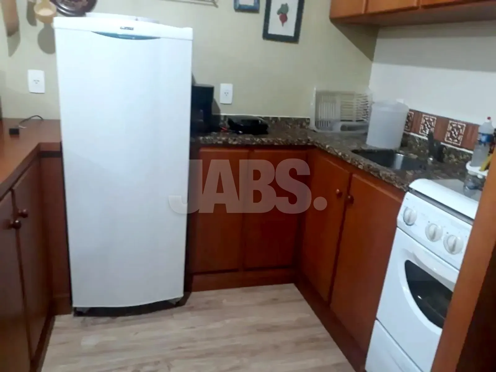 Cozinha em L com geladeira, fogão e bancada de granito