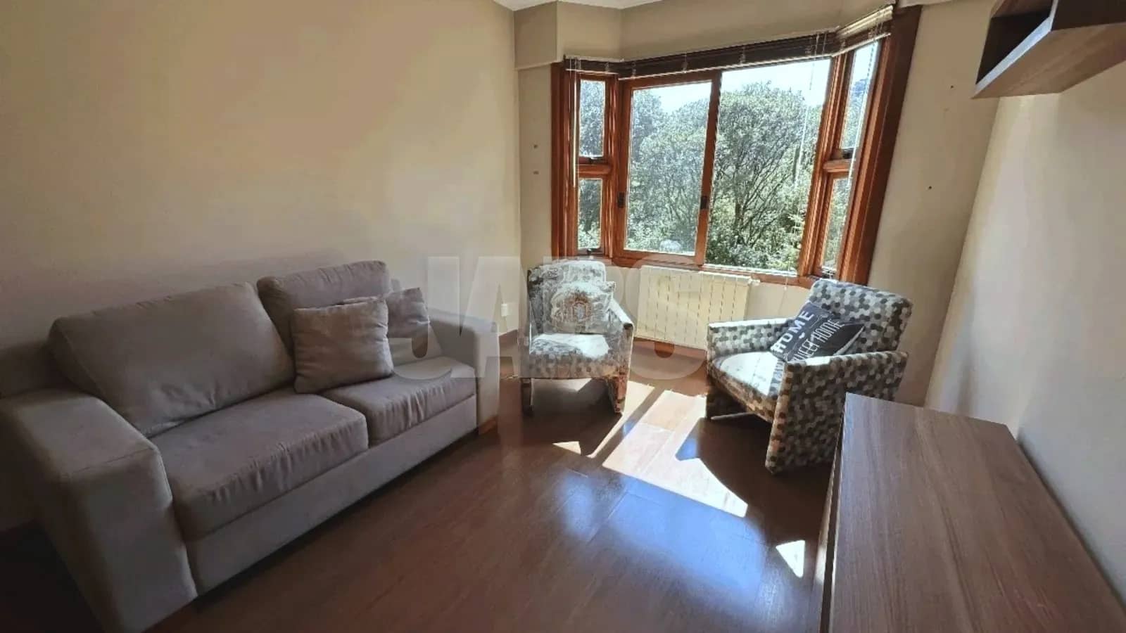 Sala com sofá, poltronas e janela para a mata