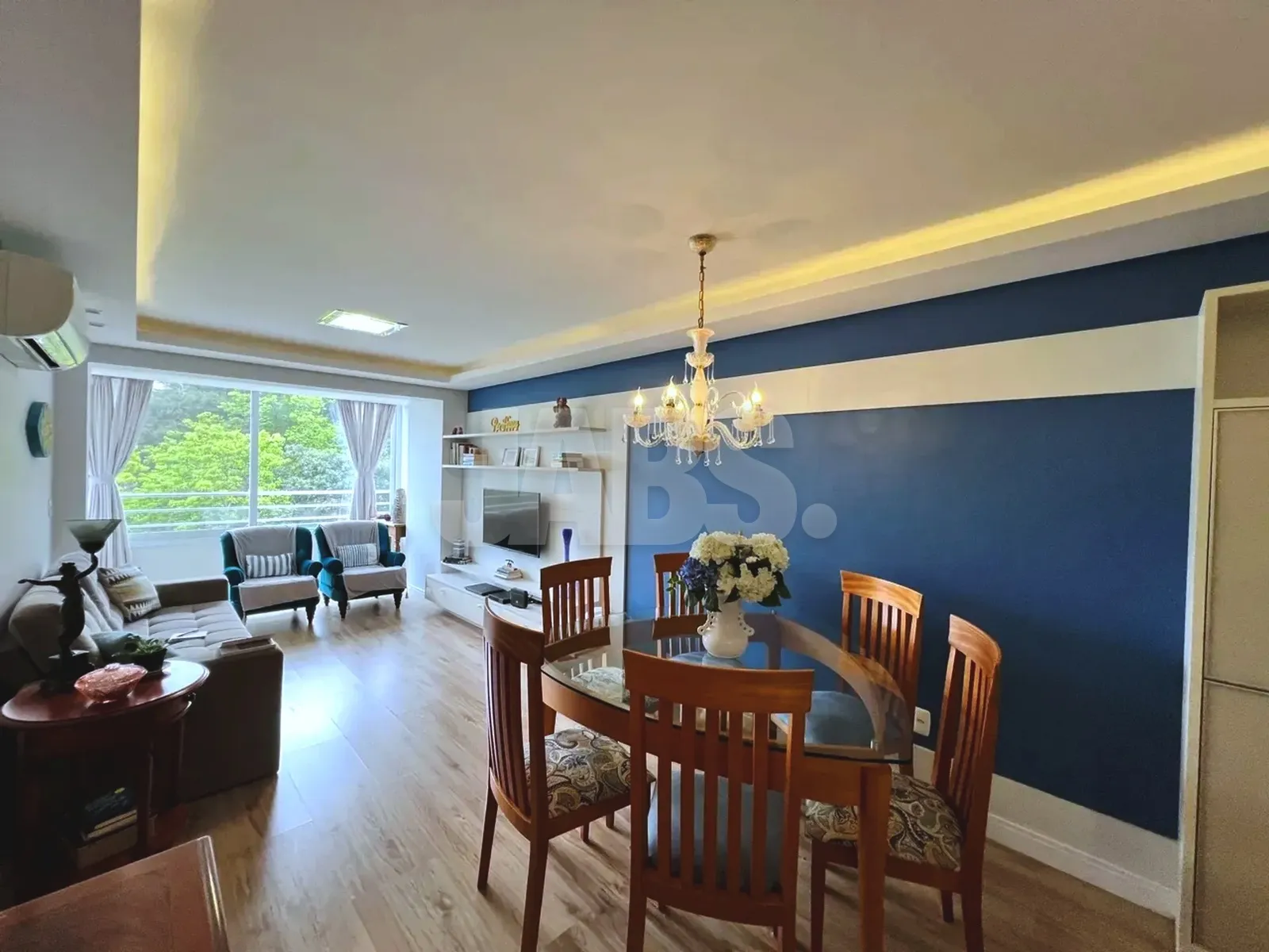 Sala de estar e jantar integradas com parede azul e lustre