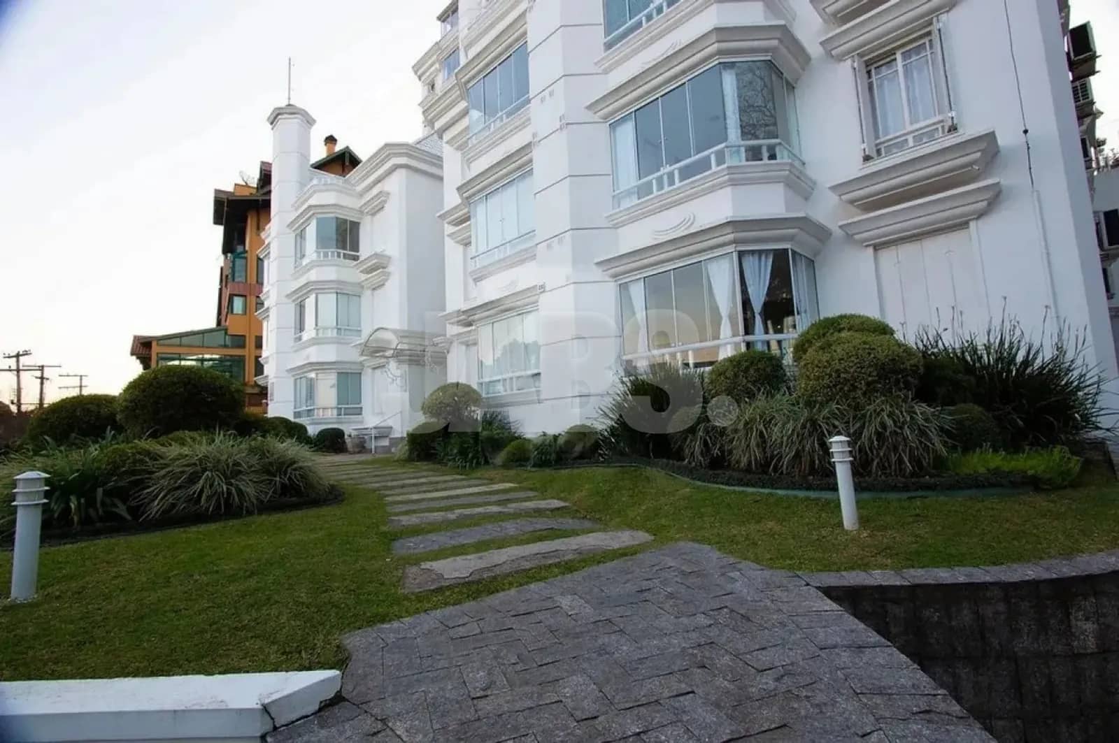 Fachada branca do prédio com jardim