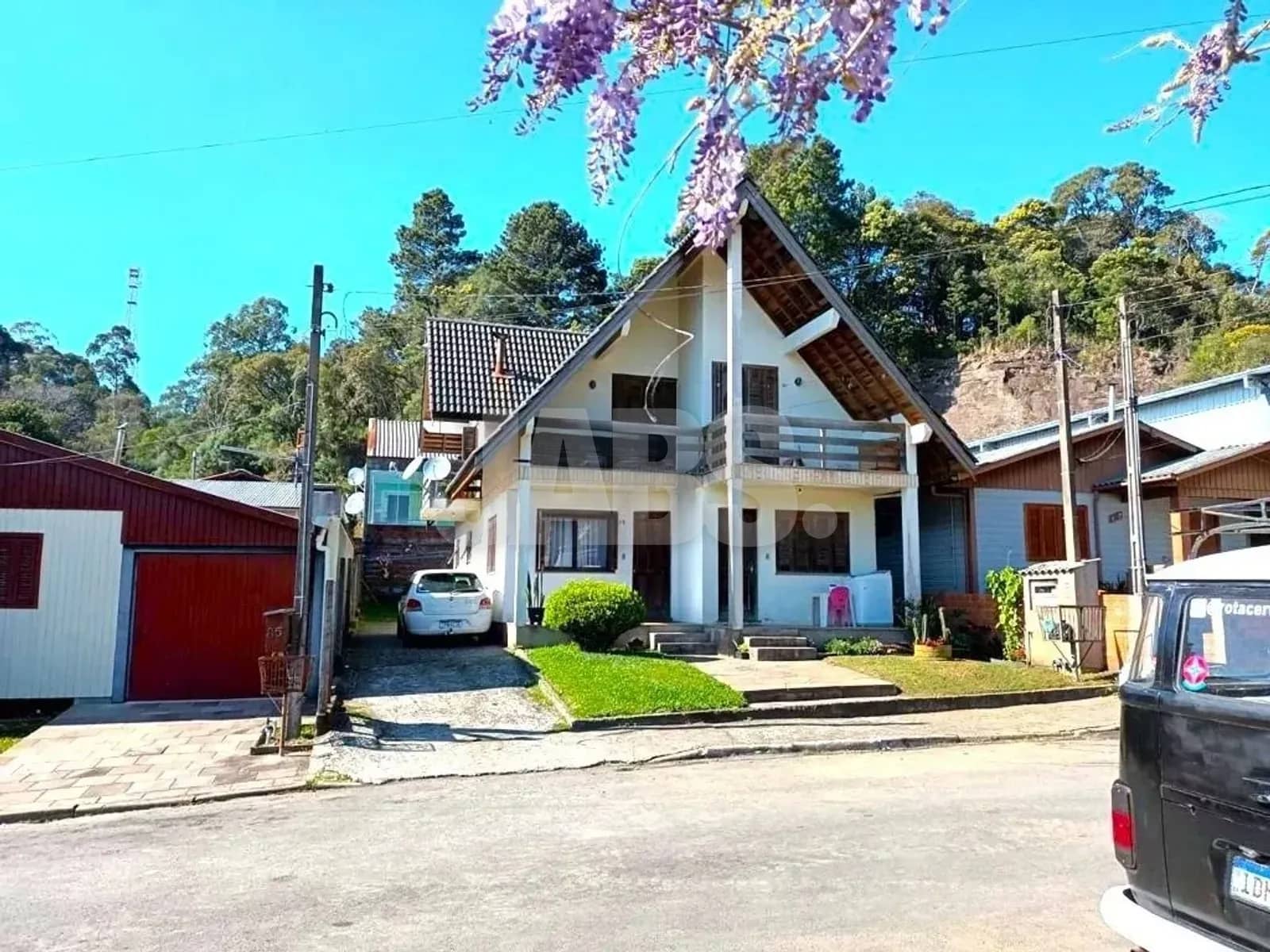 Casa de dois pavimentos vista da rua, com jardim e garagem na frente