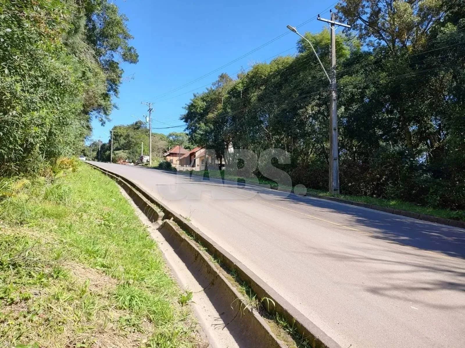 Rua do bairro com postes de luz e casas ao fundo