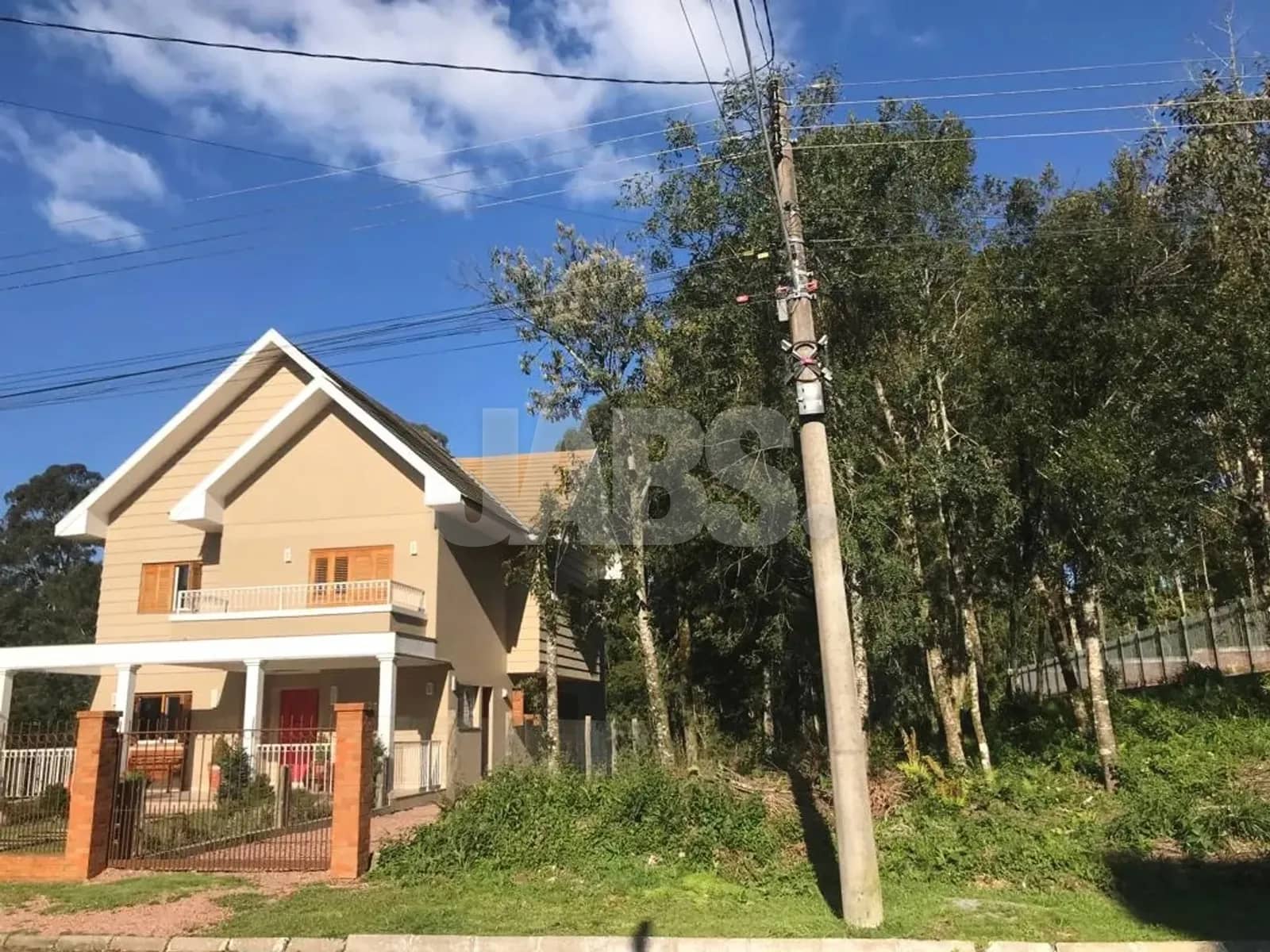 Terreno arborizado ao lado de casa em estilo serrano