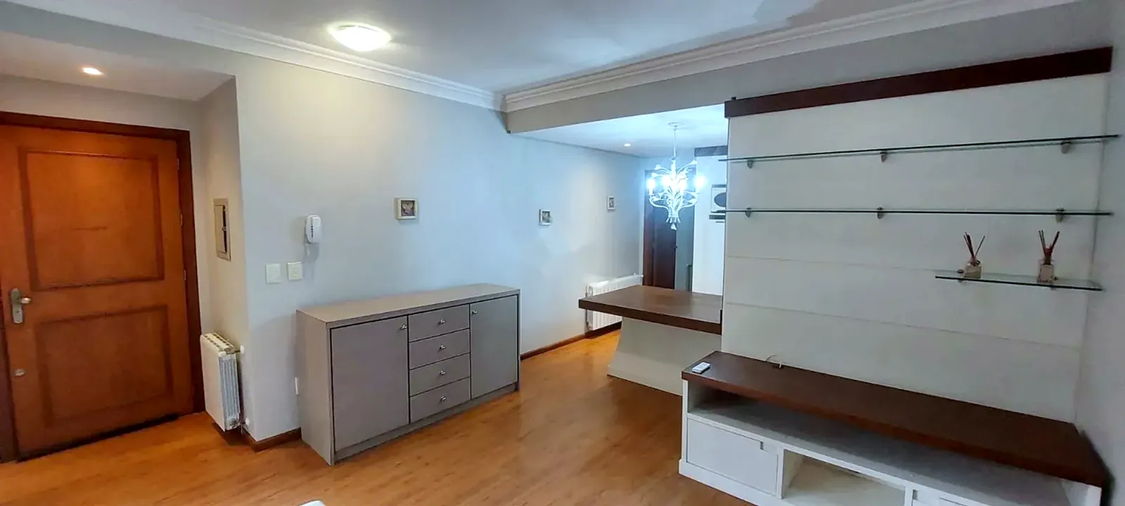 Sala com porta de madeira, aparador e lustre