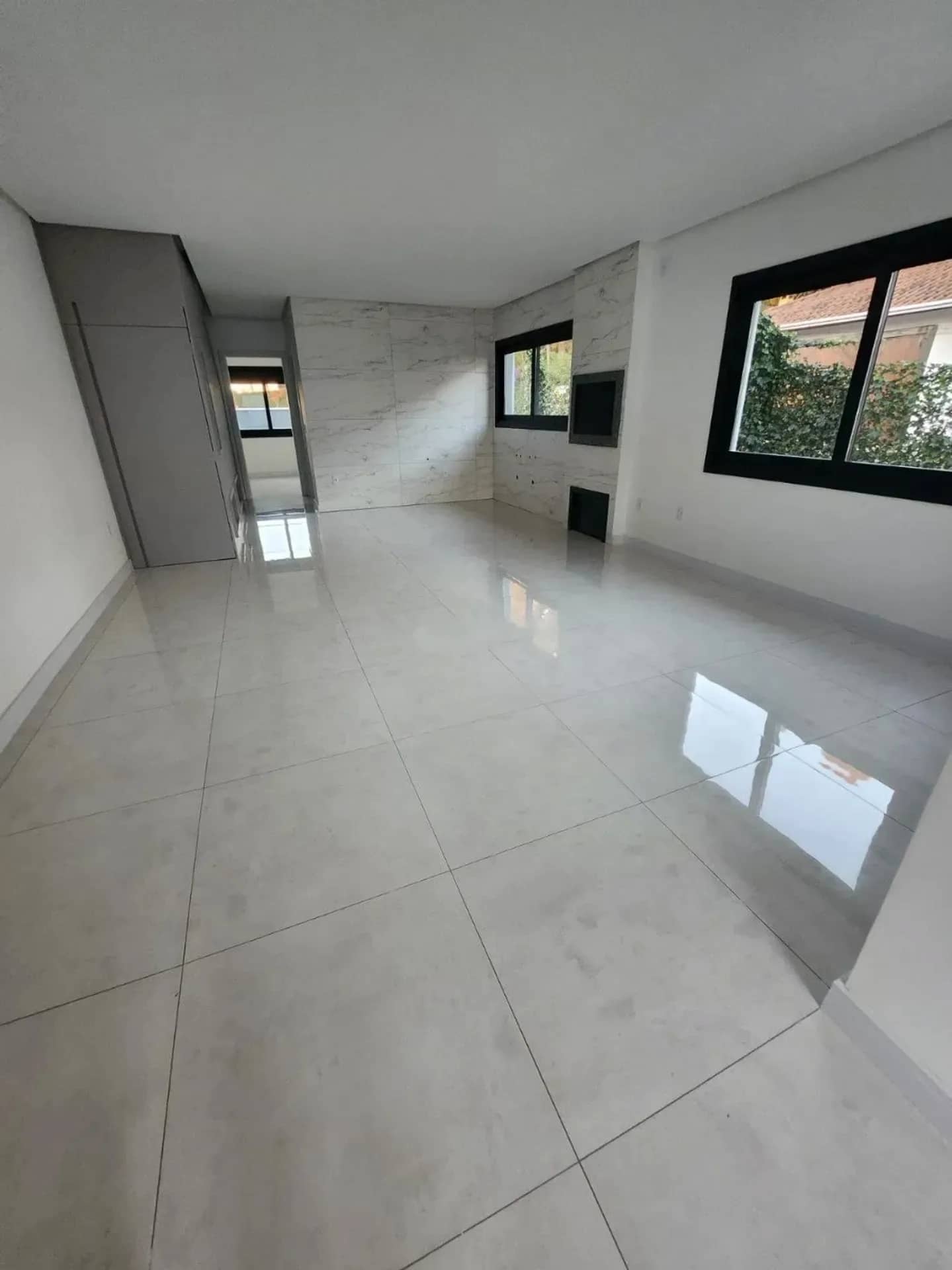 Sala ampla com porcelanato e janela para o jardim
