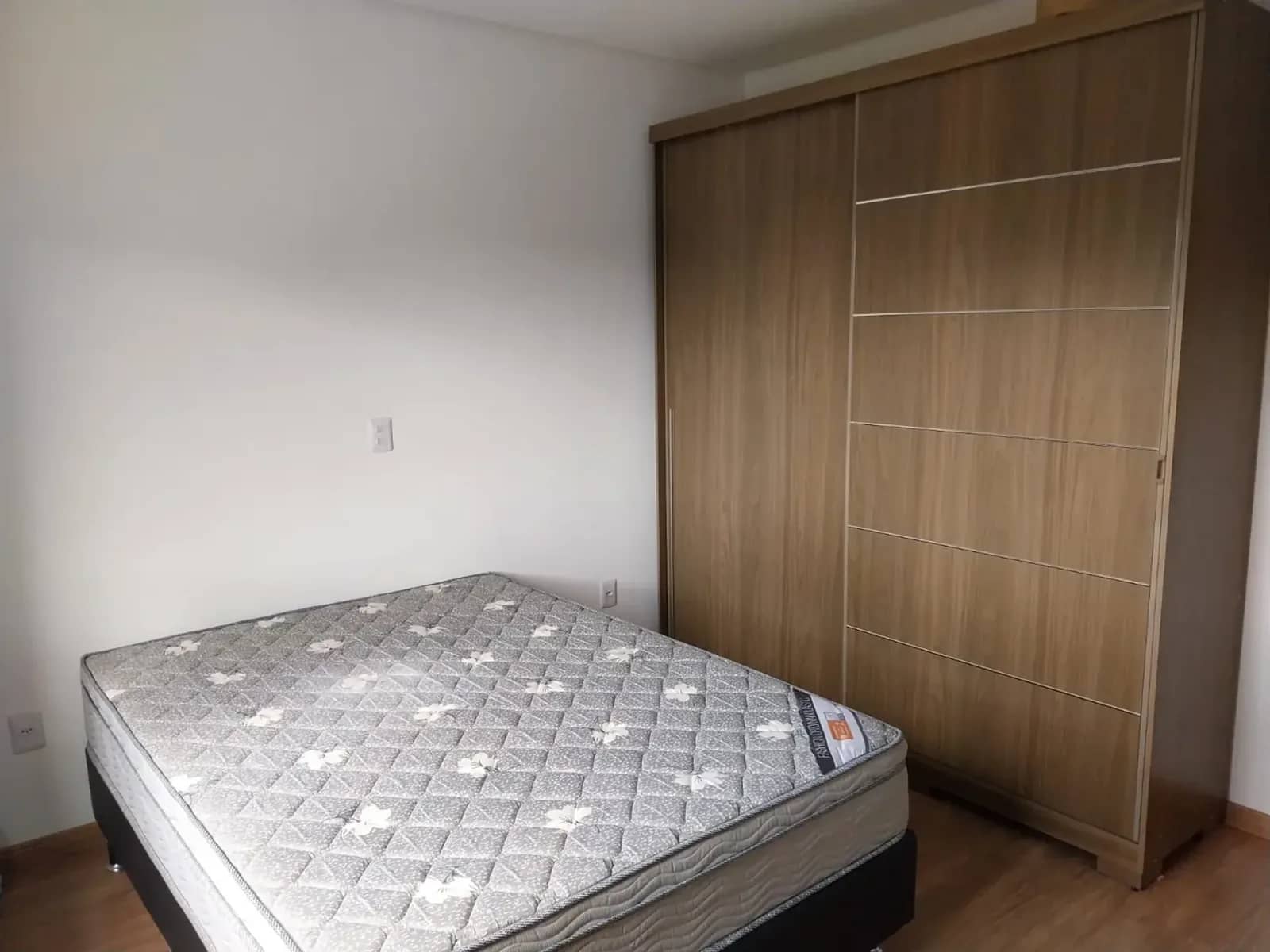 Dormitório com cama de casal e guarda-roupa amadeirado de portas de correr