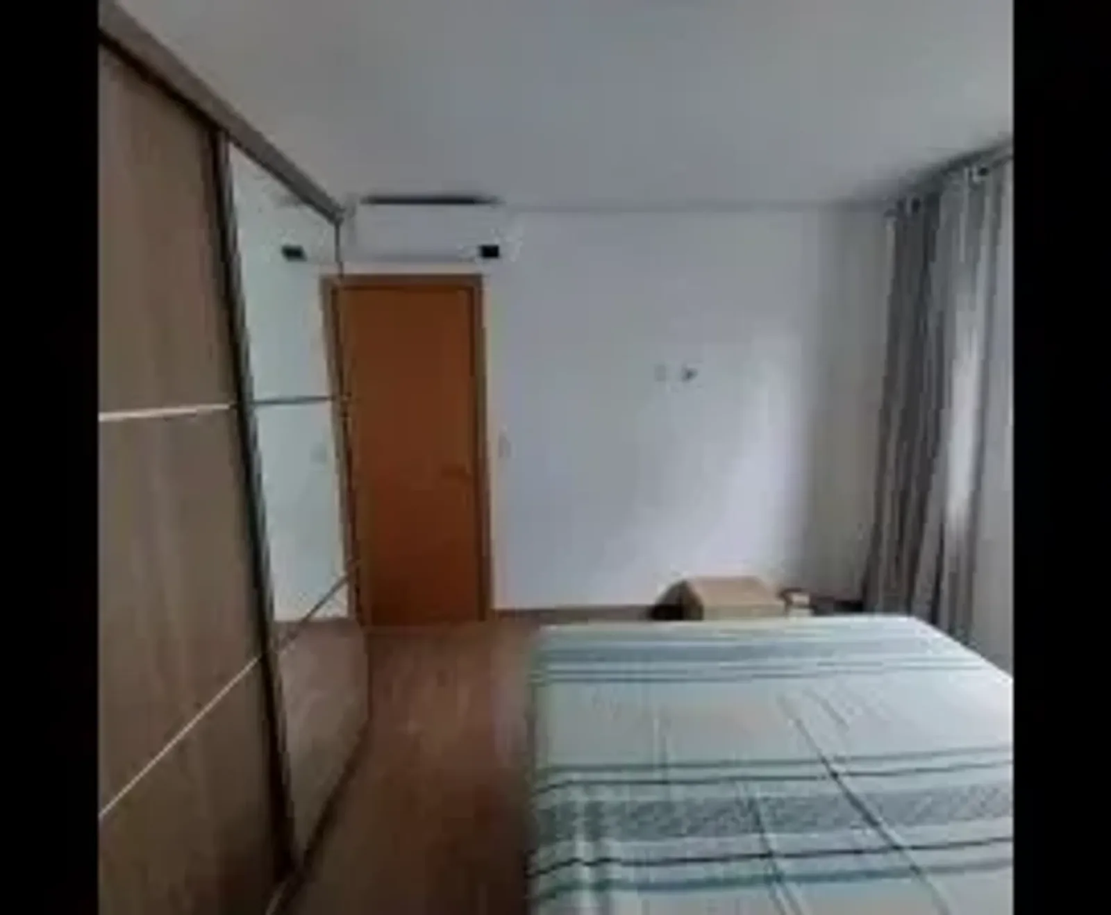 Dormitório com guarda-roupa espelhado, cama de casal e ar-condicionado split