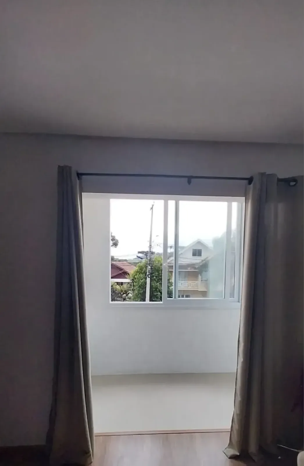 Janela ampla com cortinas e vista para o bairro