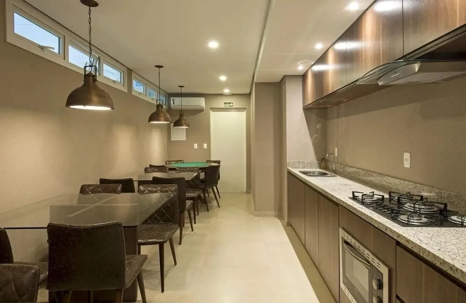 Salão do prédio com mesa de jogos, mesa longa e cozinha equipada