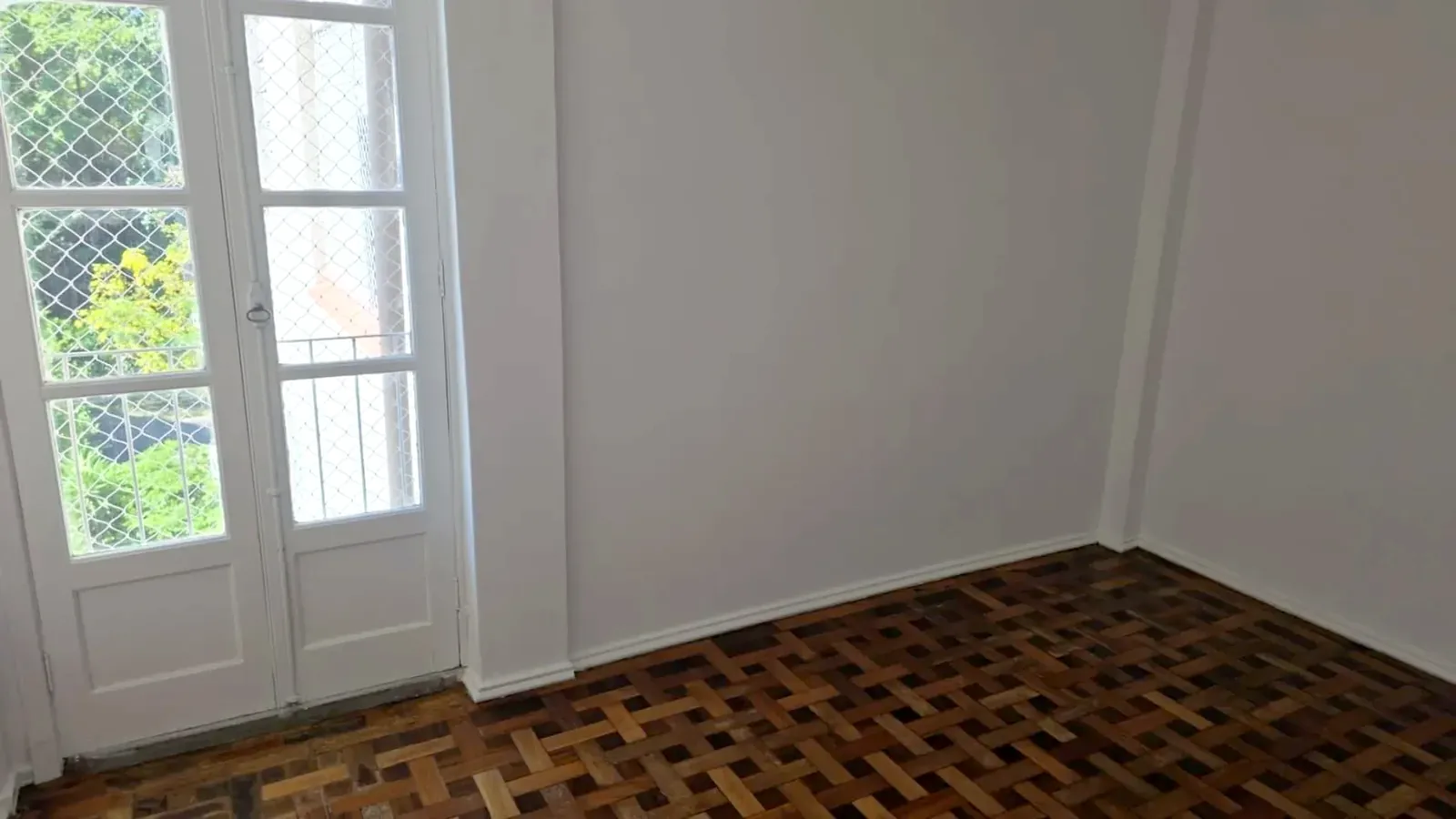 Ambiente com piso de parquê e portas para a sacada