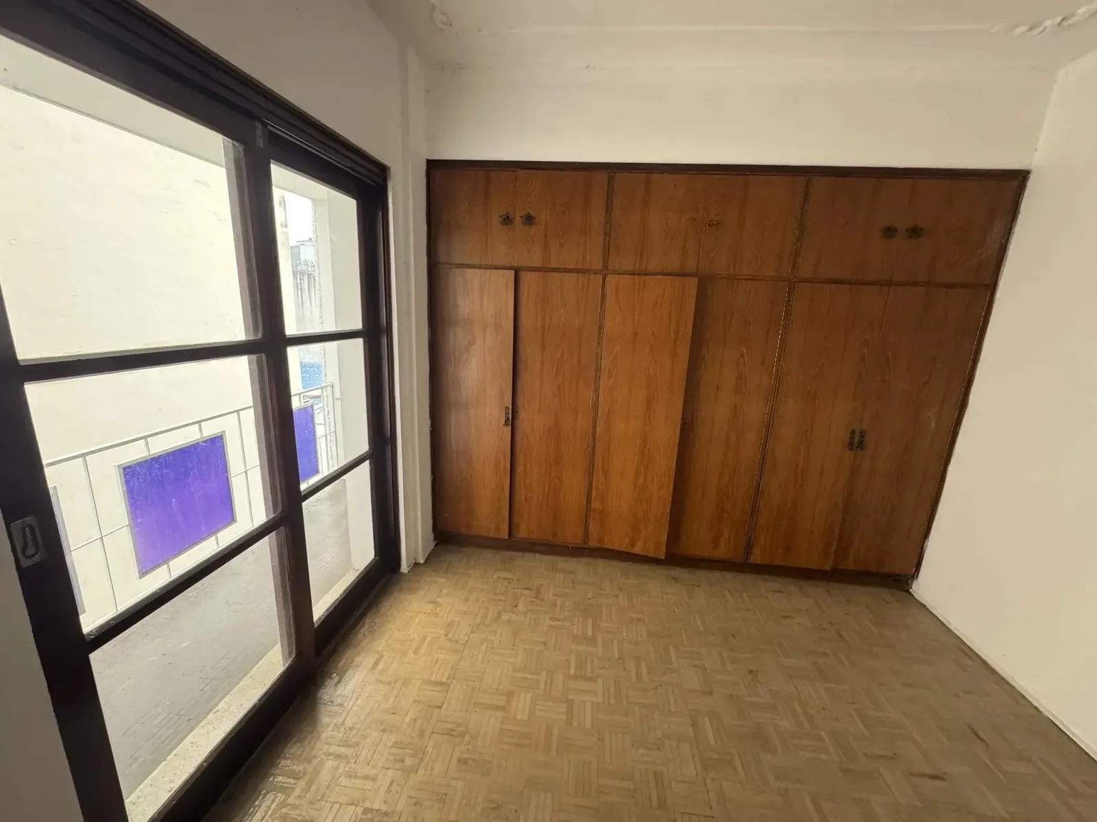 Dormitório com armário de parede inteira e porta para a sacada