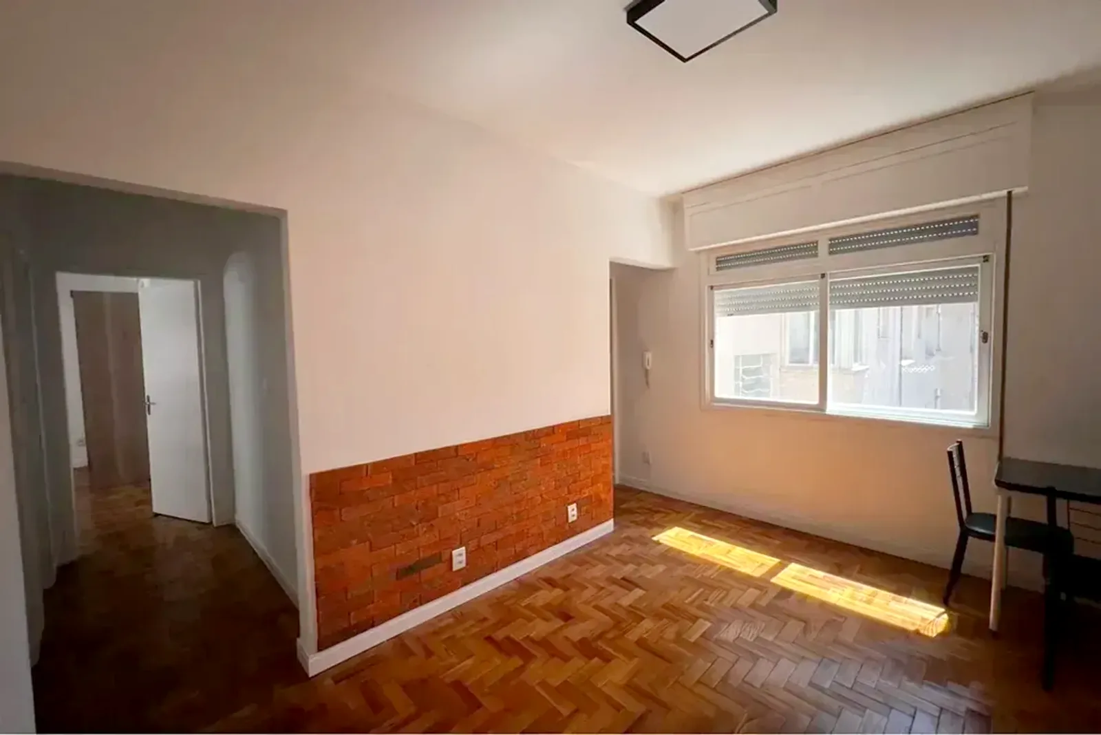 Sala do apartamento com piso de parquê e meia parede de tijolinho, na Cidade Baixa
