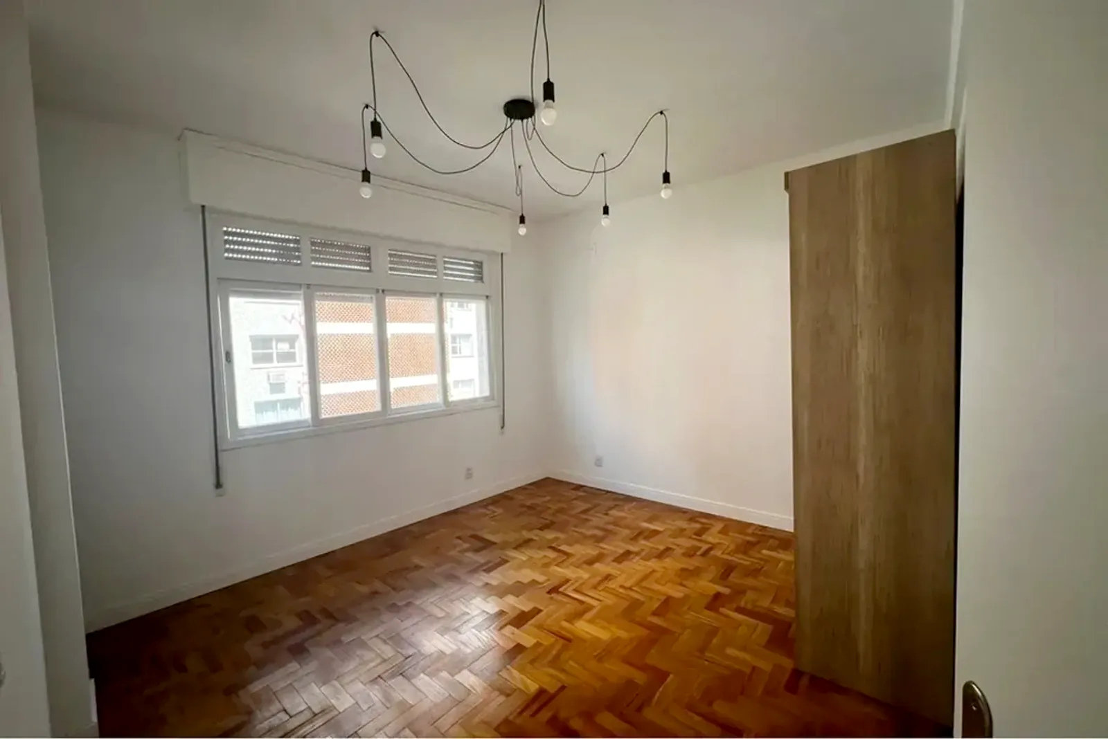 Dormitório com piso de parquê e janela ampla
