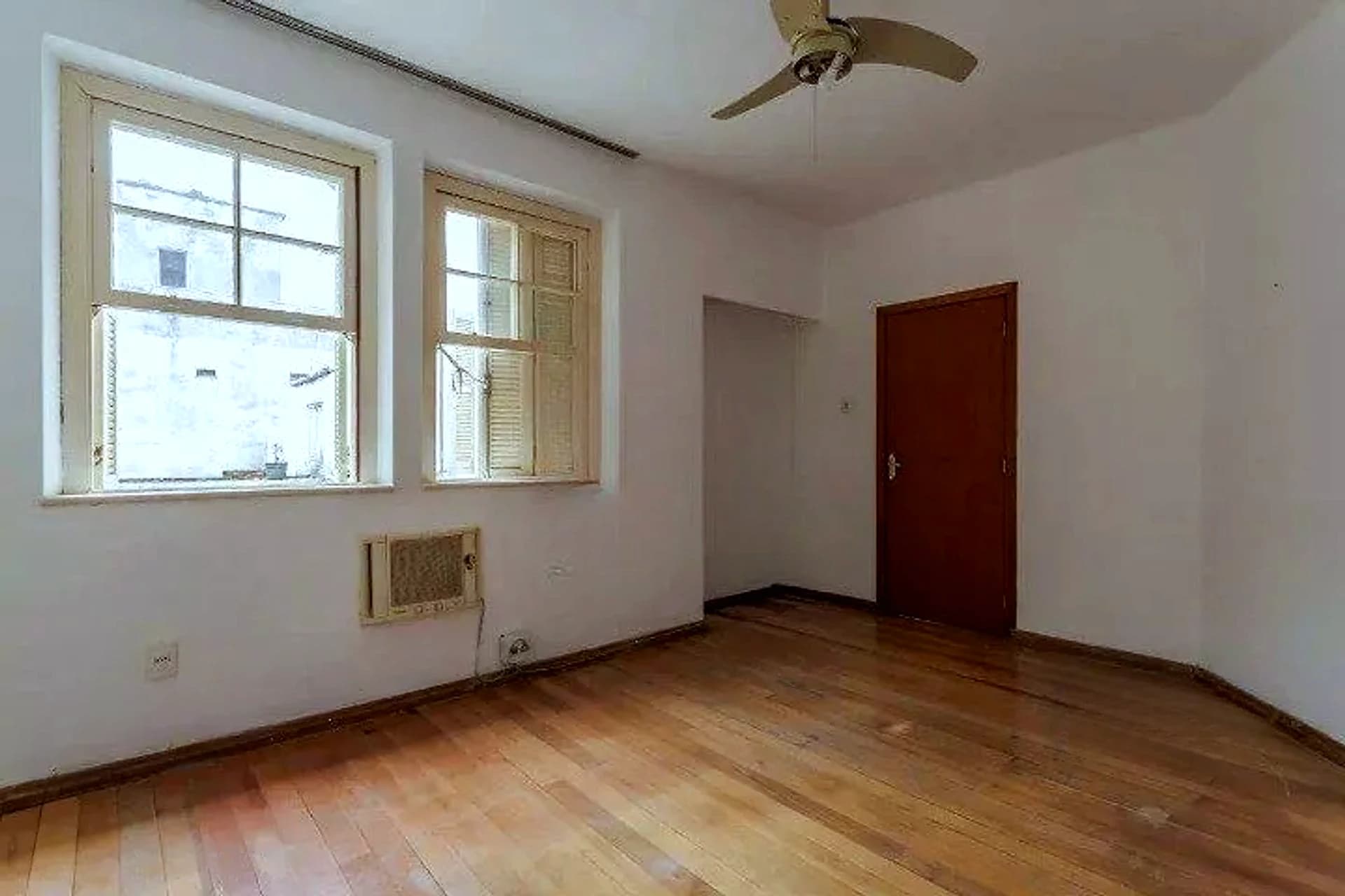 Living com piso de tabuão e janelas amplas