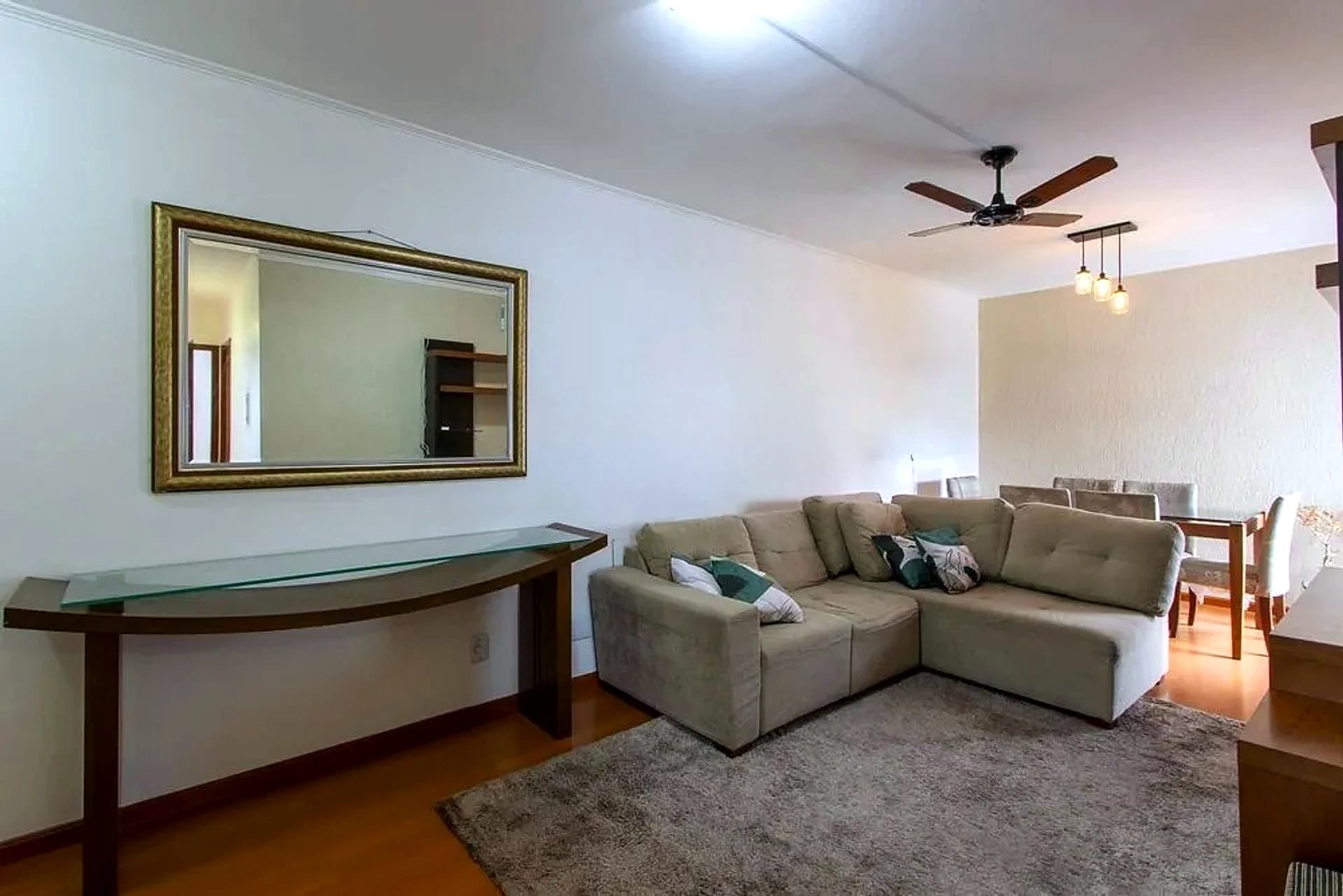 Living com espelho e piso laminado