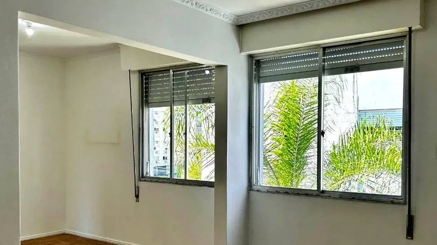 Living do apartamento com janelas largas e piso de parquê, no Menino Deus
