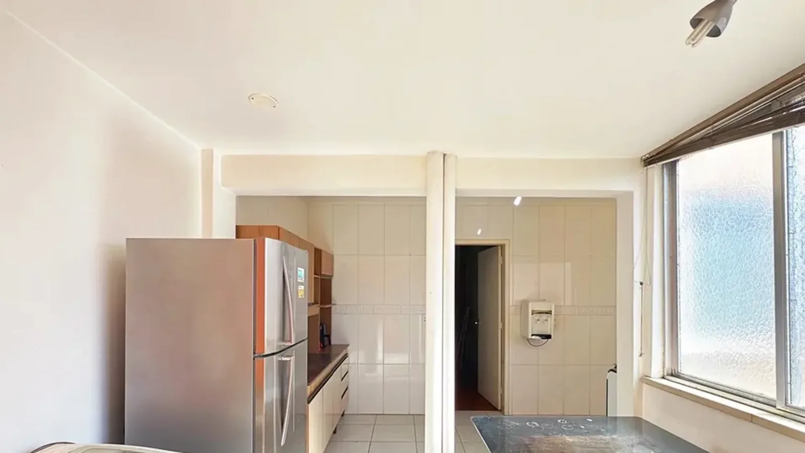 Cozinha com geladeira e área de serviço